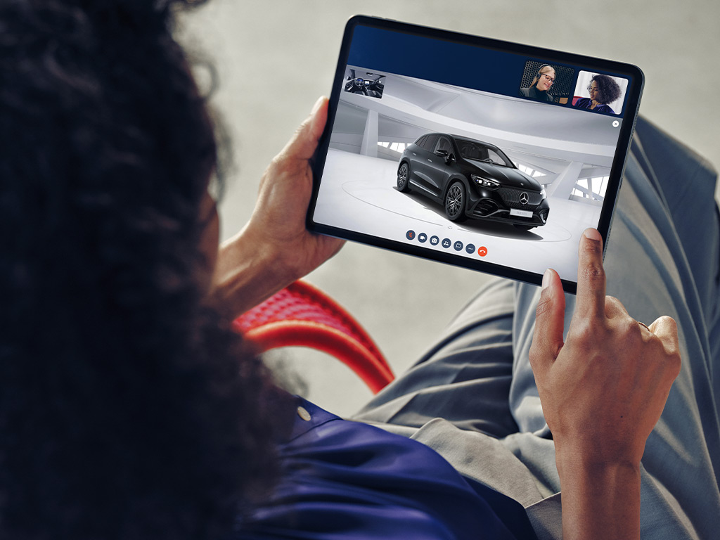 Online-Fahrzeugberatung | Mercedes-Benz. Eine Frau schaut auf ihr Tablet, auf dem eine Fahrzeugberatung läuft.