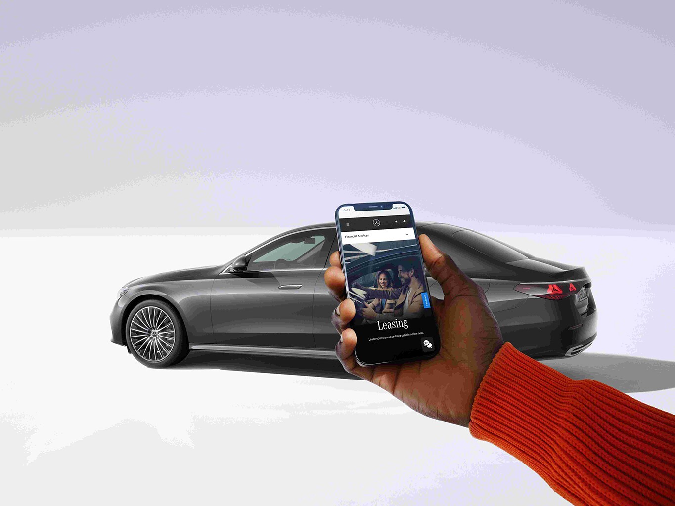 Ein Auto von Mercedes-Benz im Hintergrund. Davor eine Person mit Handy in der Hand auf dem ein Leasingangebot zu sehen ist.