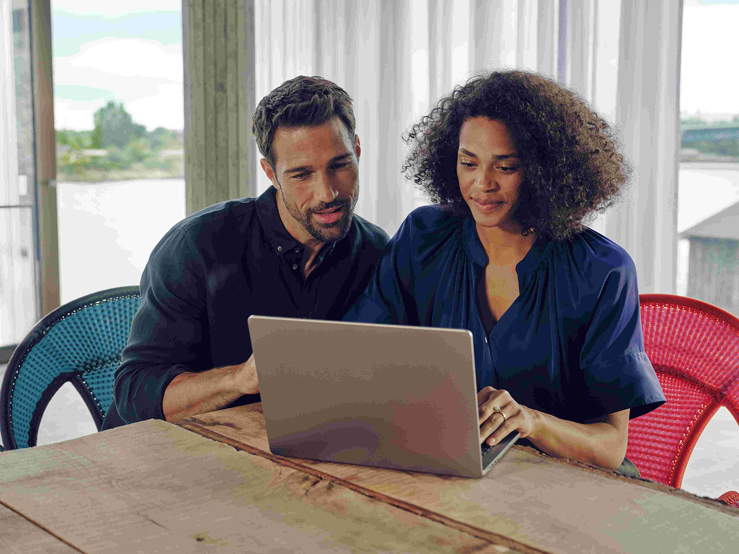 Neuwagen kaufen - so geht's! | Mercedes-Benz Ein Mann und eine Frau sitzen an einem Tisch und schauen aufmerksam auf einen Laptop.