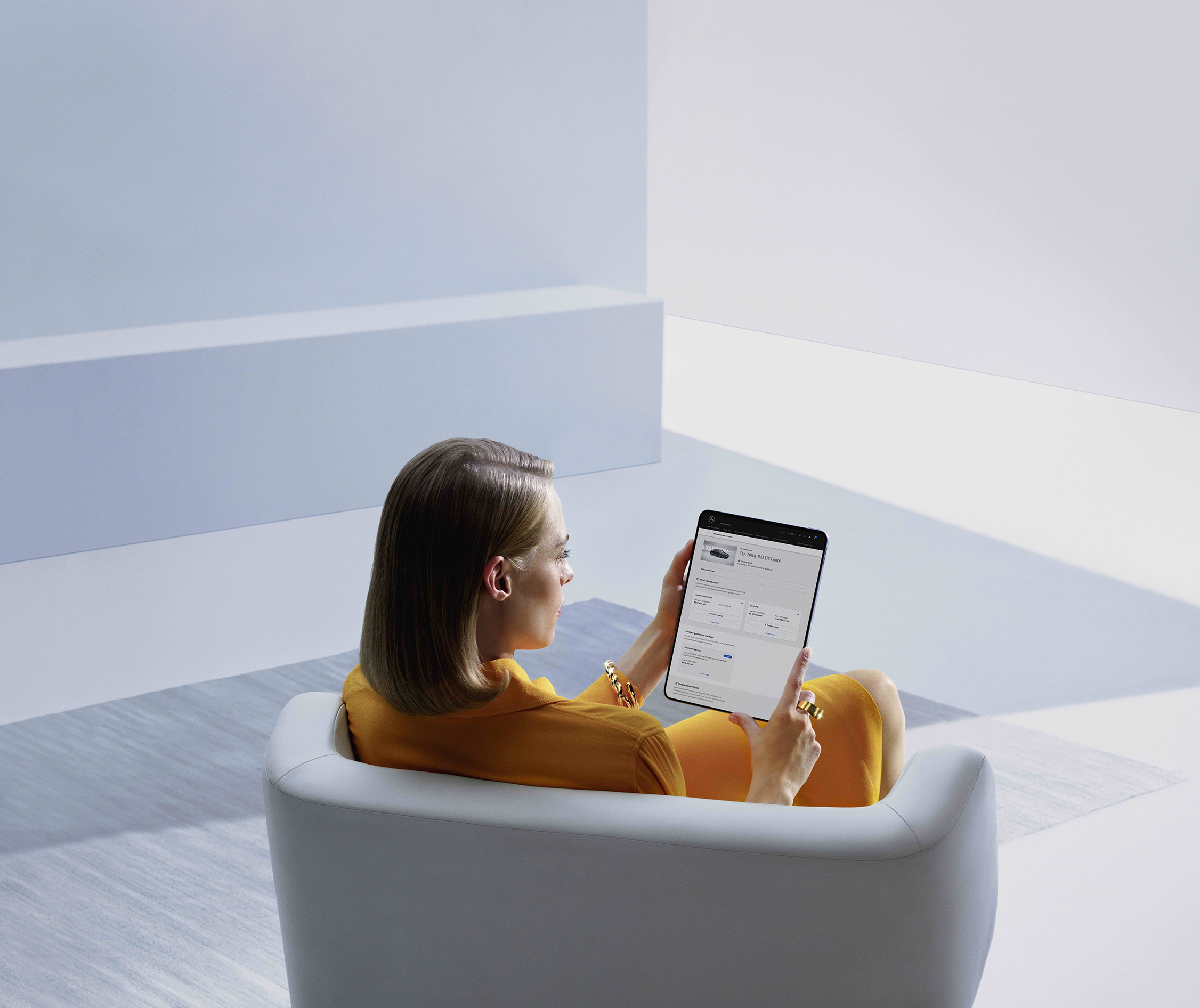 Neuwagen kaufen - so geht's! | Mercedes-Benz Ein Mann sitzt an seinem Schreibtisch und schaut auf seinen Laptop in einem hellen Raum.