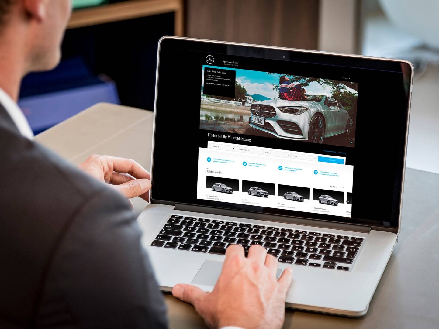 Ein Mann sitzt an seinem Schreibtisch und schaut auf seinen Laptop.