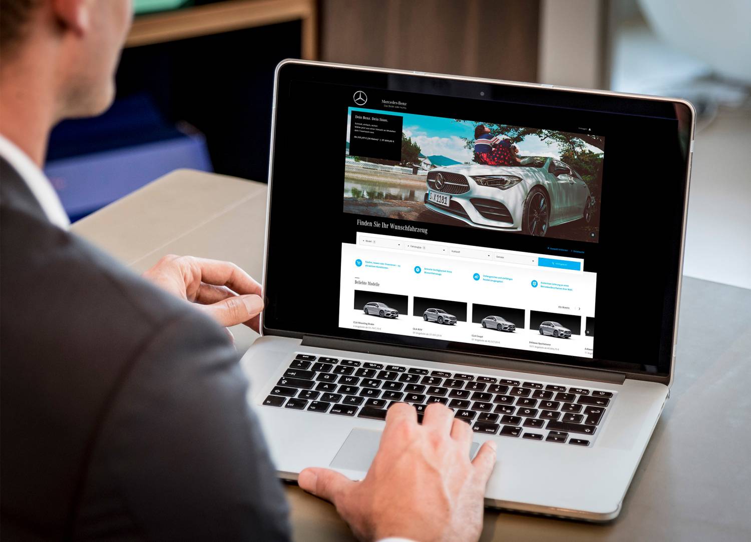 Neuwagen kaufen - so geht's! | Mercedes-Benz Ein Mann sitzt an seinem Schreibtisch und schaut auf seinen Laptop.