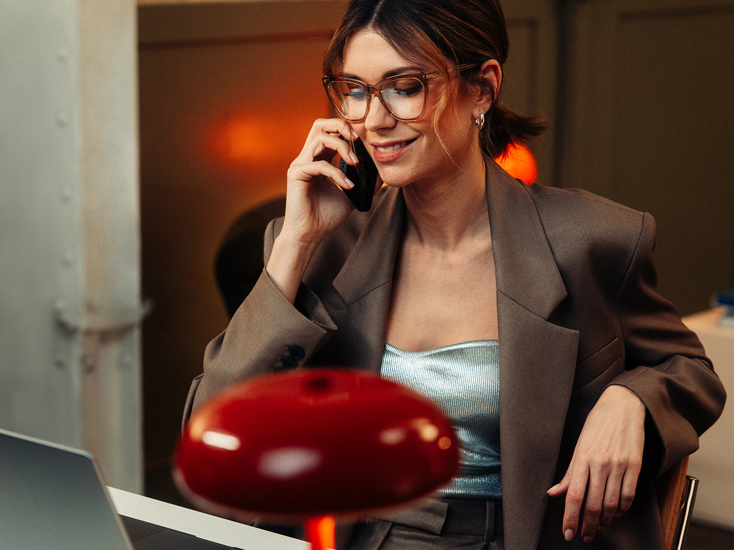 Kontakt | Mercedes-Benz. Eine Frau sitzt auf einem roten Stuhl und telefoniert.