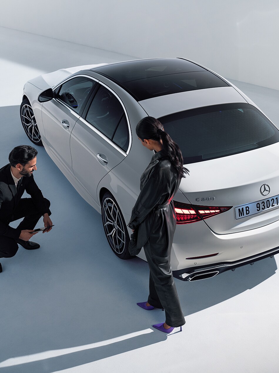 Zwei Personen schauen auf das linke Hinterrad von einem Mercedes-Benz.