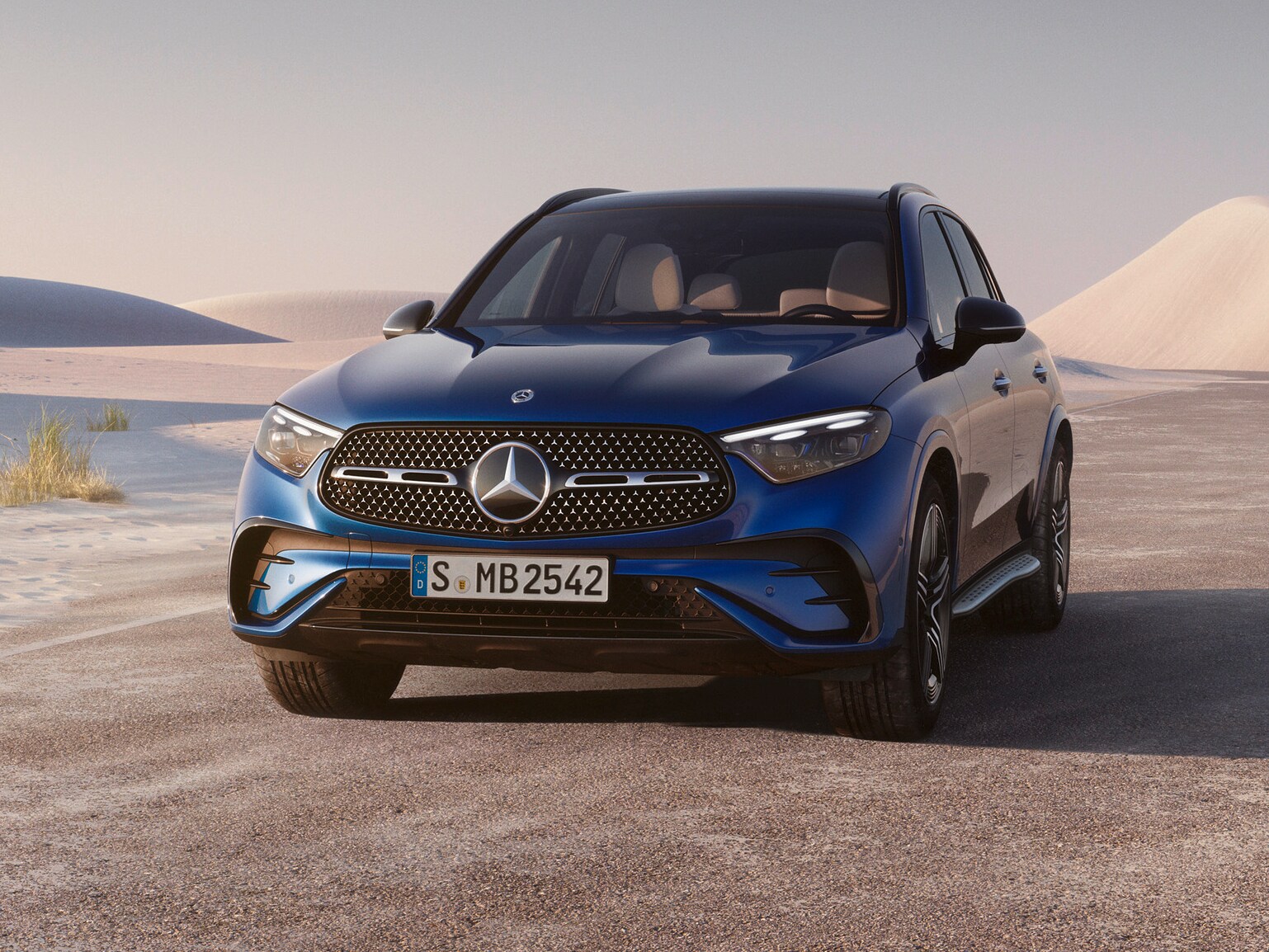 Ein blauer GLC SUV in frontaler Ansicht inmitten einer sandigen Wüstenlandschaft.