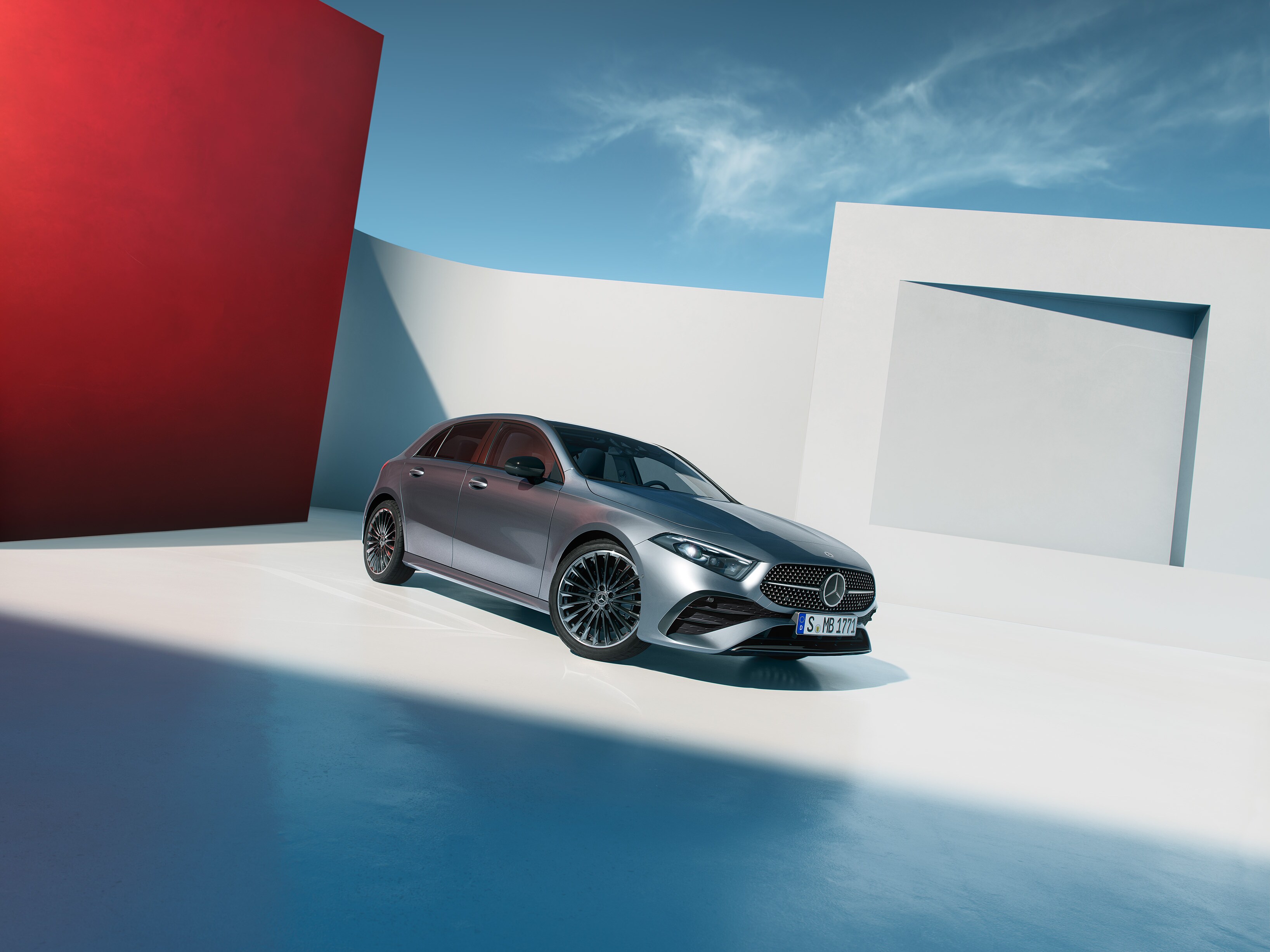 Eine silbergraue A-Klasse Kompaktlimousine vor einem weißen Gebäude.