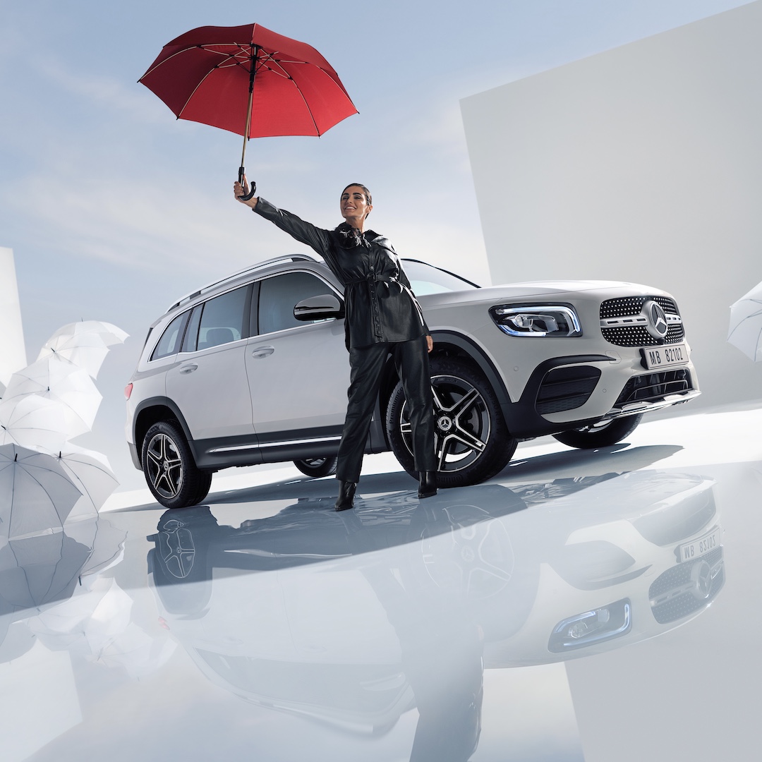 Mercedes-Benz Store | Mercedes-Benz. Eine Frau hält einen roten Regenschirm weit über ihren Kopf.