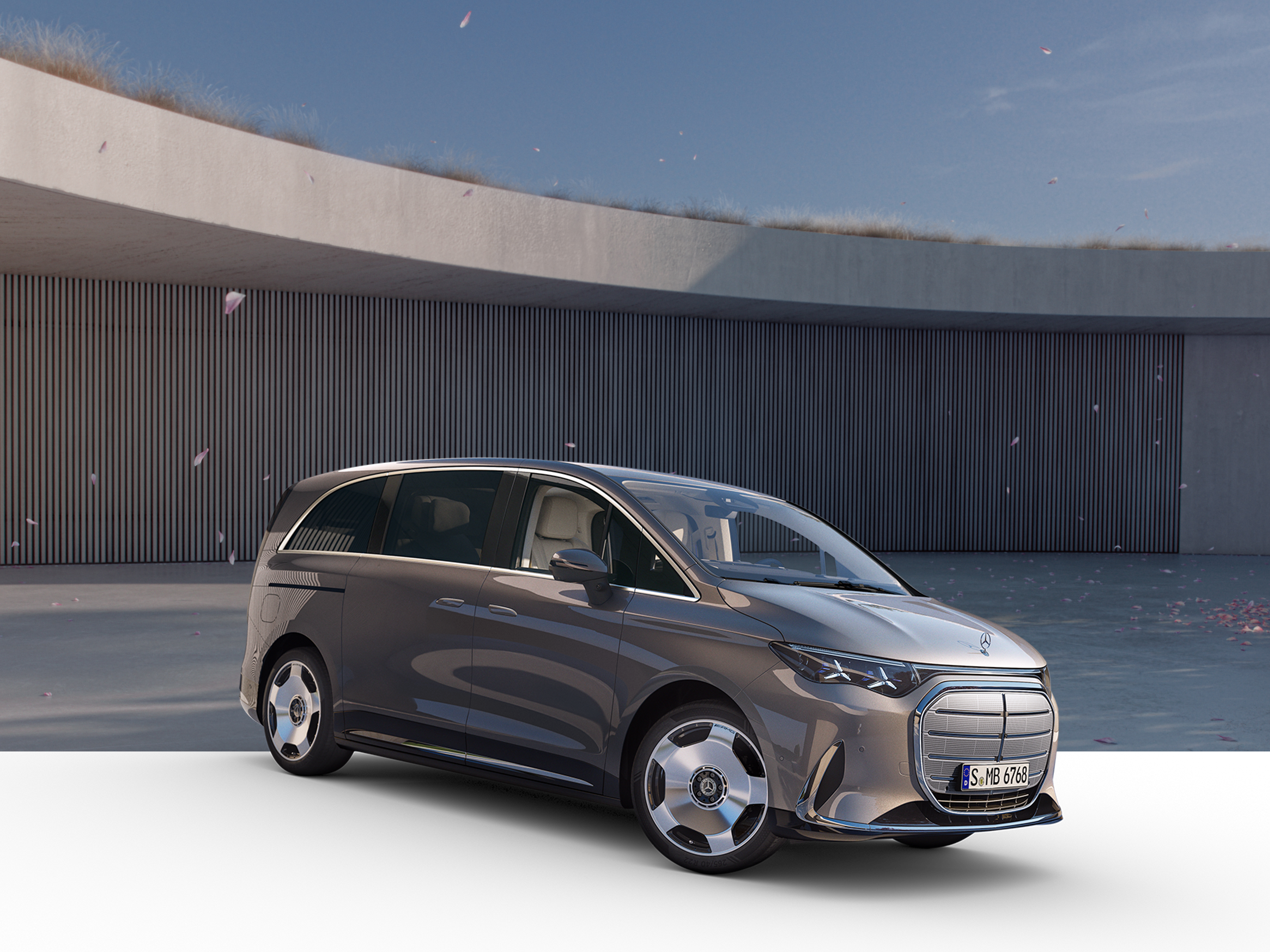 Gezeigt wird halb Freigestellter VLE von Mercedes-Benz. Parkend vor einem modernem Gebäude mit einem Kirschbaum an der Seite.