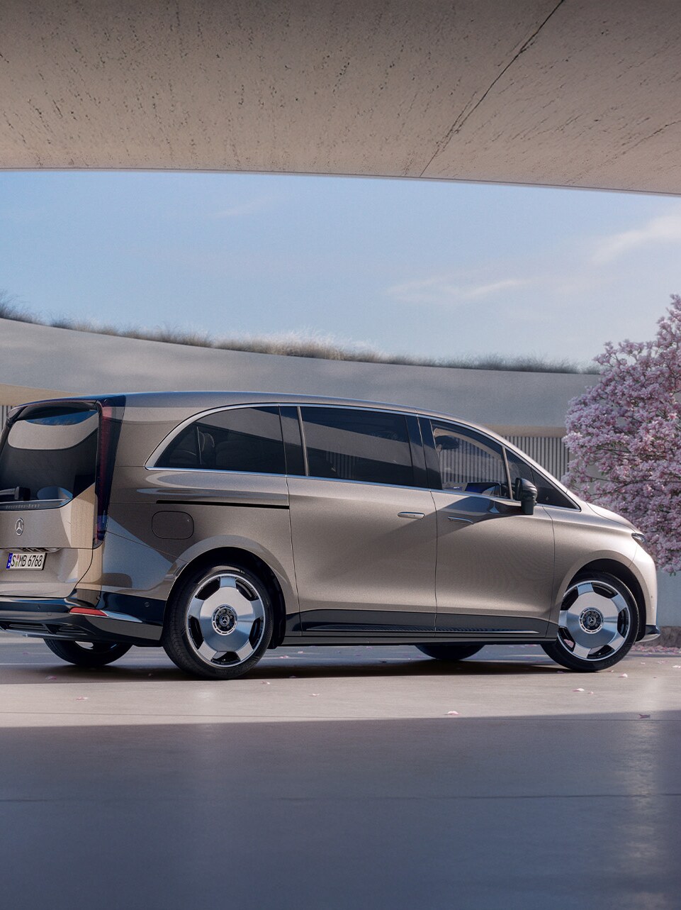 Gezeigt wird der VLE von Mercedes-Benz. Parkend vor einem modernem Gebäude mit einem Kirschbaum an der Seite.