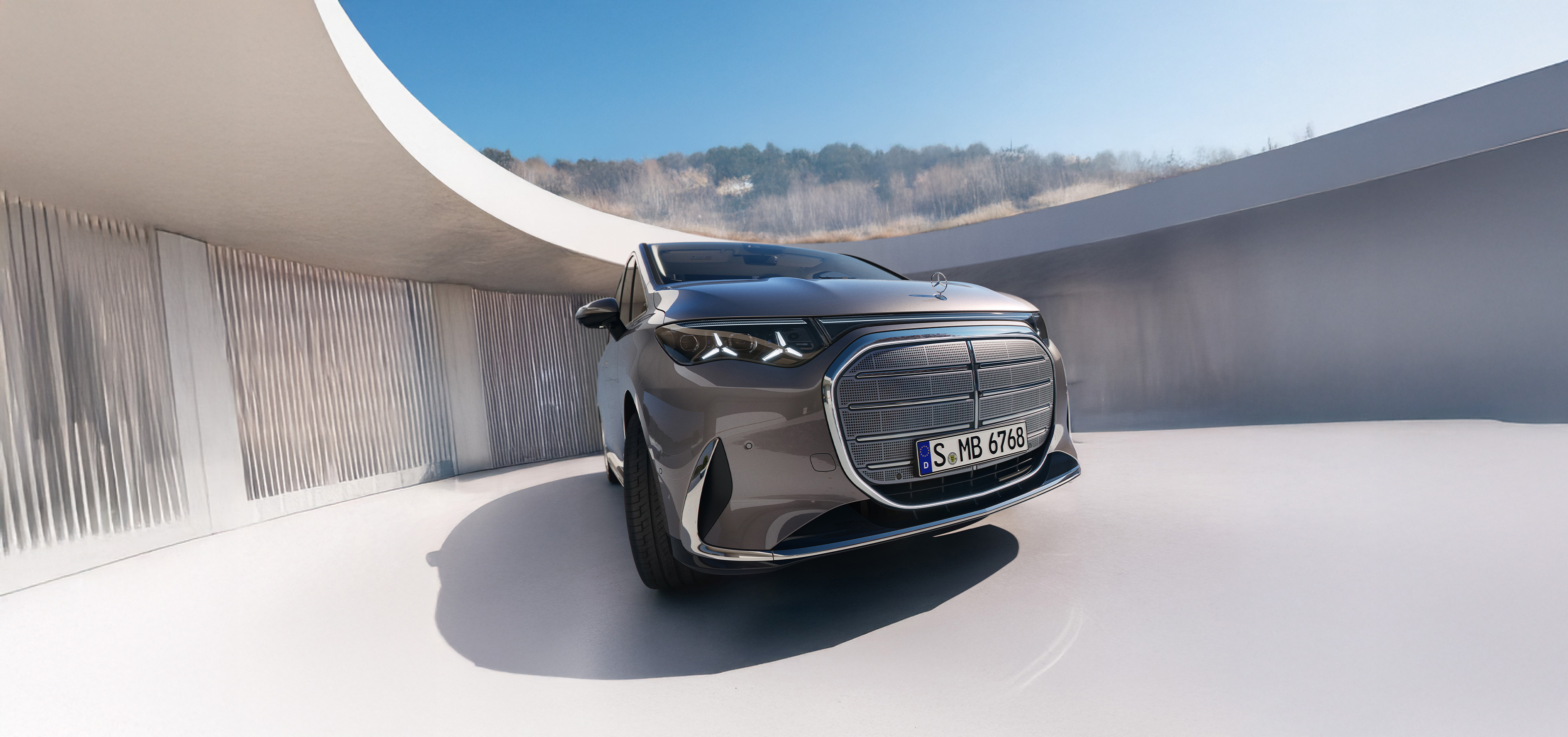 VLE | Mercedes-Benz Gezeigt wird der VLE von Mercedes-Benz. Parkend vor einem modernem Gebäude mit einem Kirschbaum an der Seite.