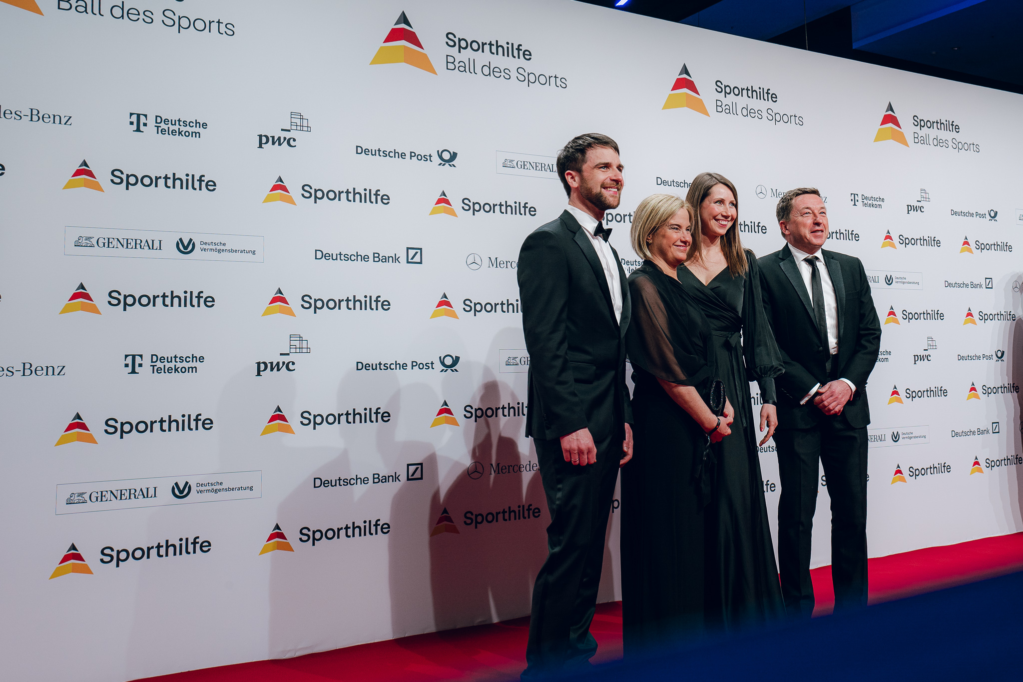 Deutsche Sporthilfe | Mercedes-Benz Ein Gruppe Menschen vor einer Wand mit dem Deutsche Sporthilfe Logo