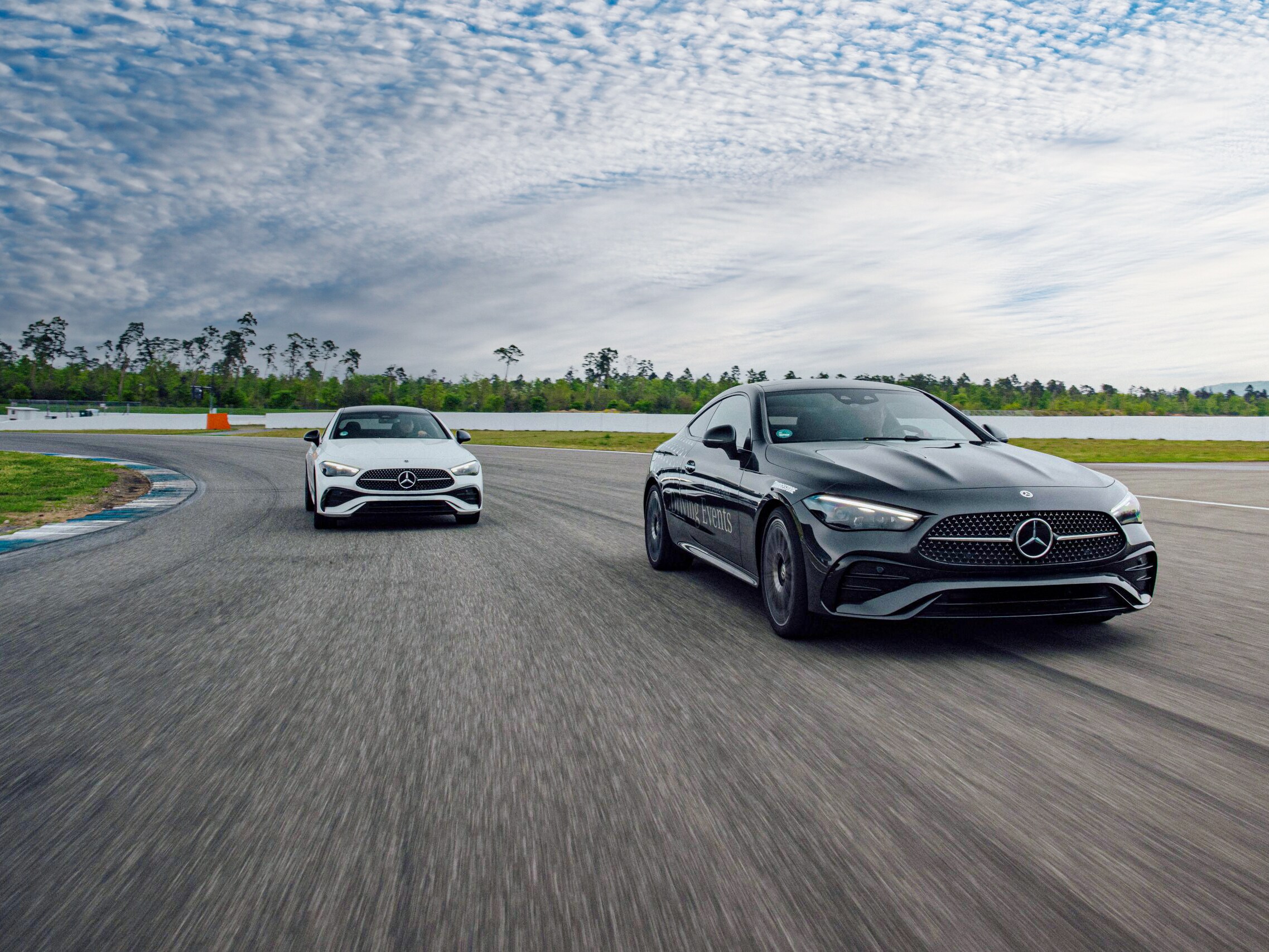 Zwei Fahrzeuge von Mercedes-Benz von vorne auf einer Rennstrecke vor einer weiten Strecke.