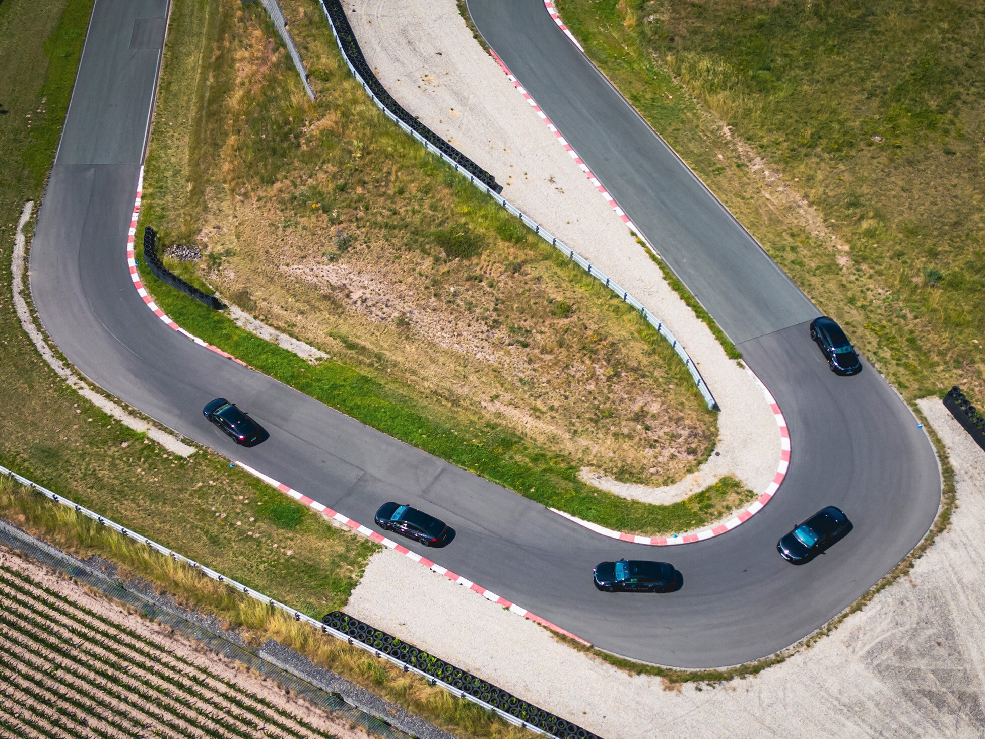 Eine Kolonne aus fünf Fahrzeugen von Mercedes-Benz fährt in Formation auf einer Rennstrecke.