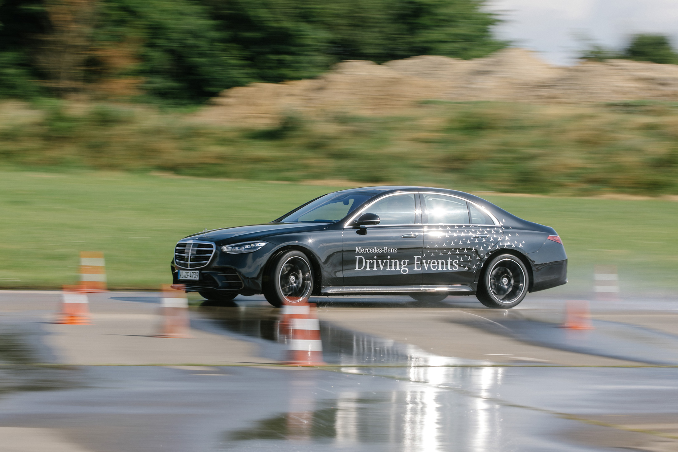 Driving Events | Mercedes-Benz Ein Fahrzeug von Mercedes-Benz fährt auf einer angelegten Fahrbahn zwischen Hütchen.