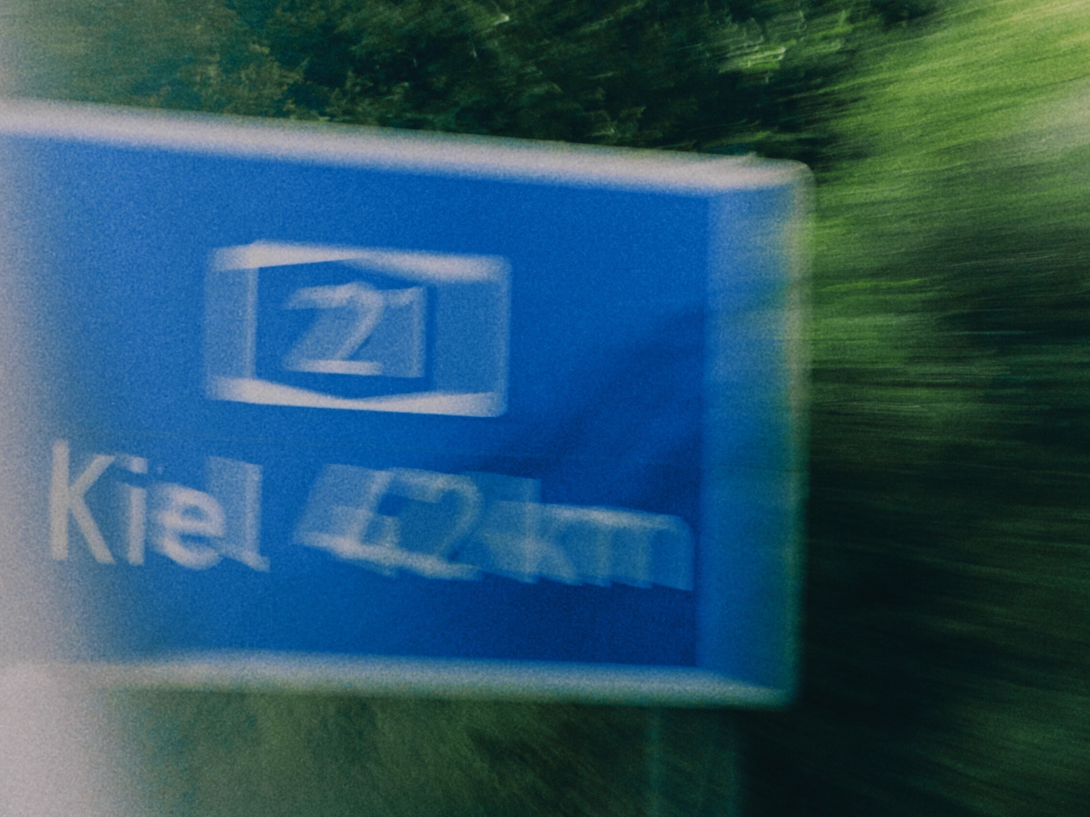 Ein blaues Autobahnschild mit der Aufschrift "Kiel 42km" ist verschwommen. 