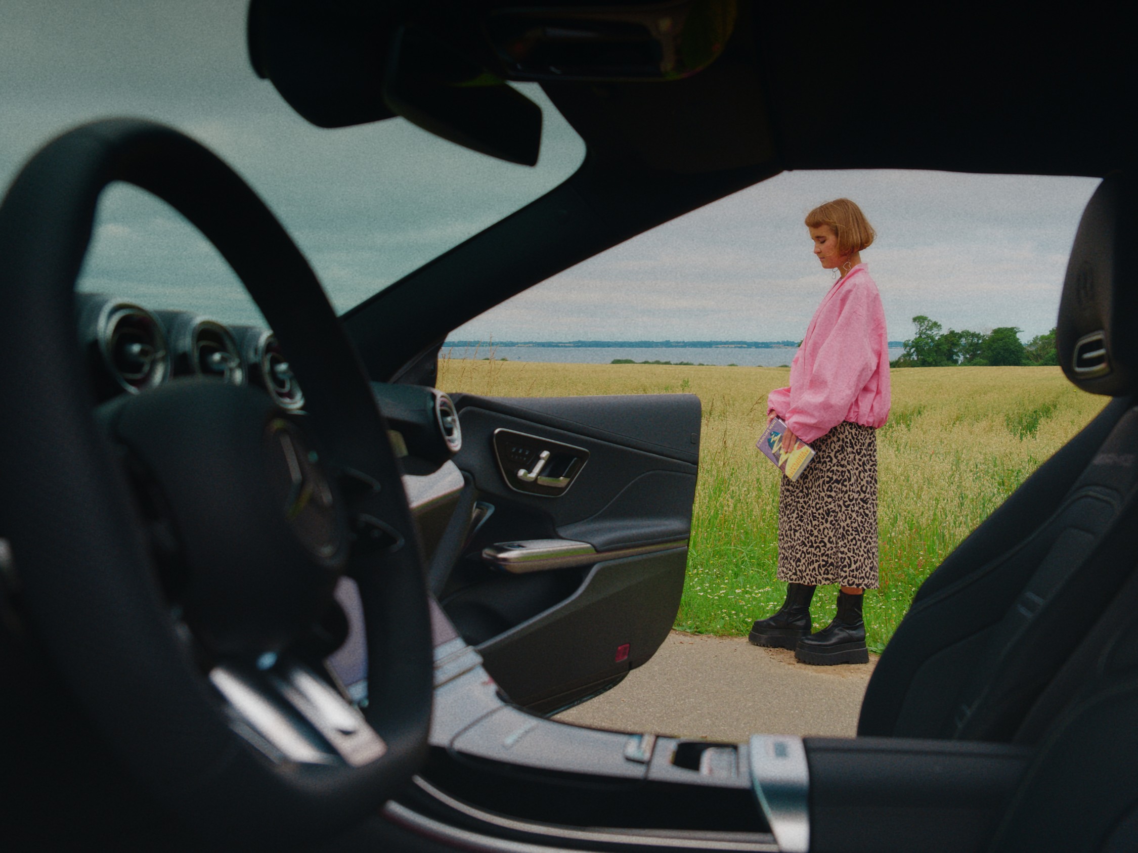Das Ziel ist der Weg von Caro Wahl | Mercedes-Benz Innesicht aus eine Mercedes-Modell mit göffneter Tür. Neben dem Auto steht Caro Wahl in der Natur.