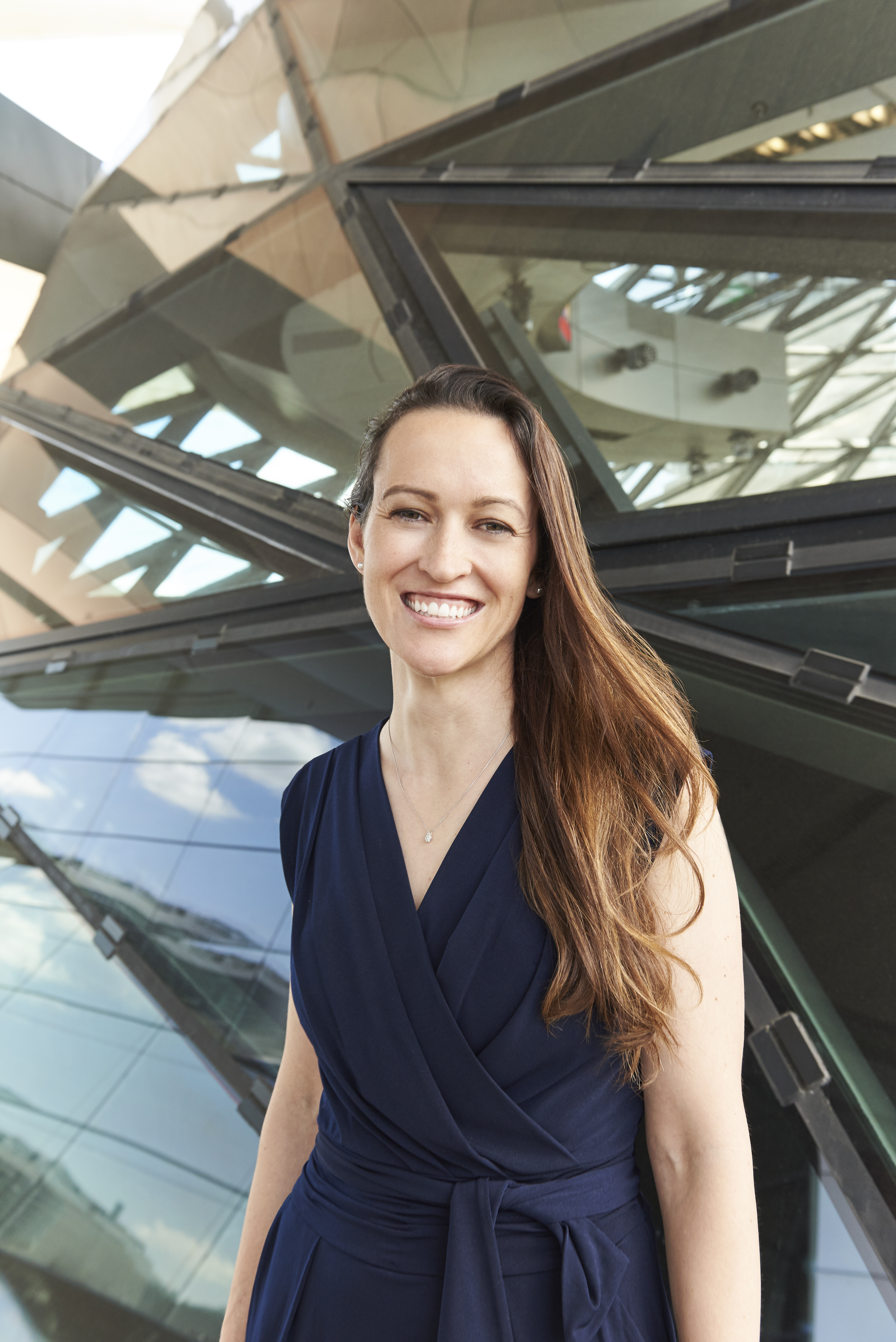 Nicola Winter | Mercedes-Benz. Portrait von Nicola Winter, die frontal in die Kamera lächelt. Sie trägt einen blauen Jumpsuit.
