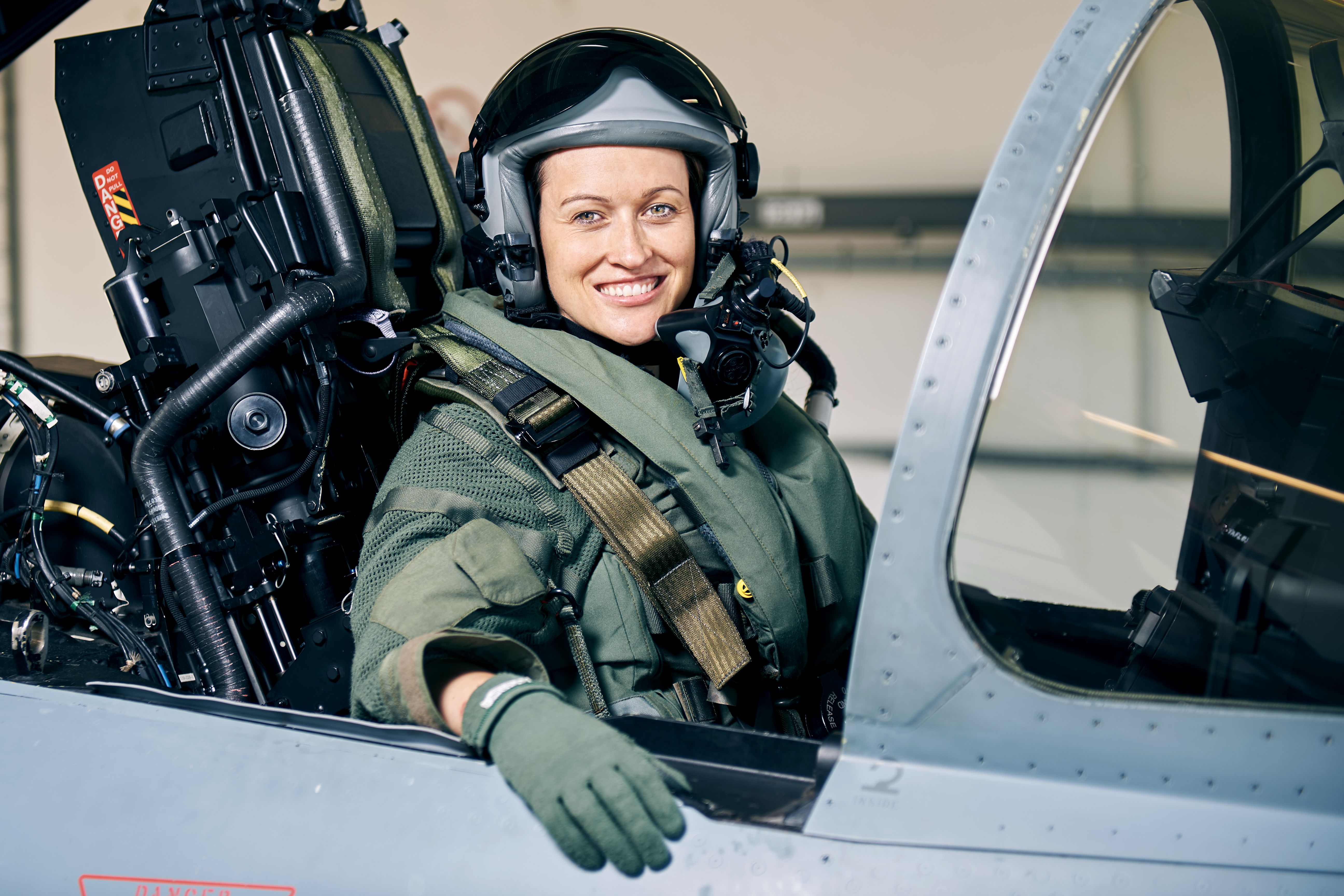Nicola Winter | Mercedes-Benz. Nicola Winter sitzt in einem Bundeswehr-Jet und lächelt dabei in die Kamera.