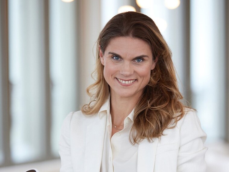 Unternehmerin Janneke Lupp steht lässig mit einer Hand in der Hosentasche und mit der anderen ein Messgerät haltend in einem Raum.