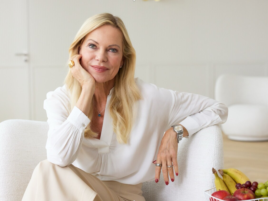 Unternehmerin Nina Ruge sitzt mit einem Messgerät auf einem weißen Sessel in einem hellen Raum.