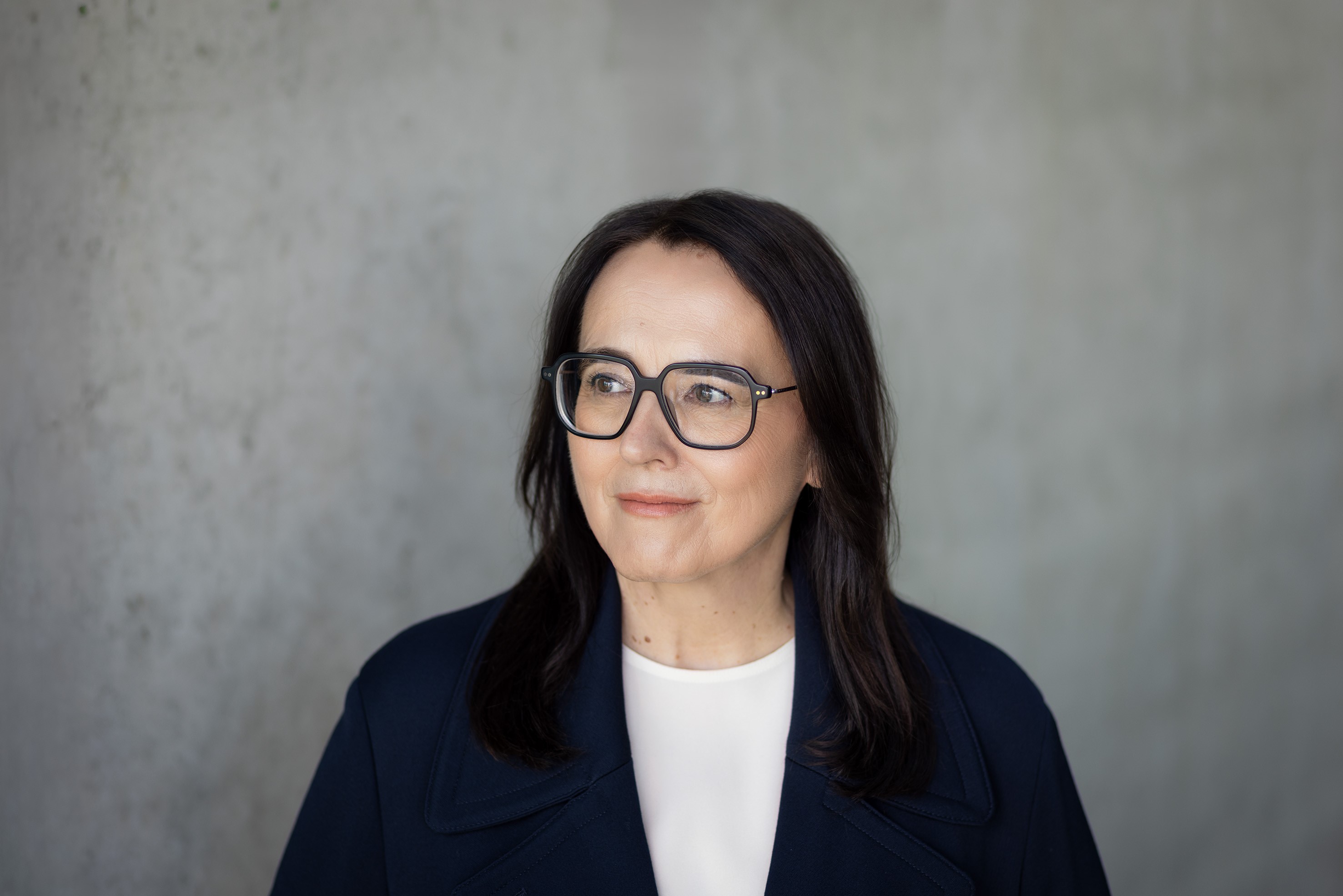 She's Mercedes Inspiration | Mercedes-Benz Potrait von Petra Bock vor einer grauen Steinwand. Petra Bock schaut nach links und lächelt.