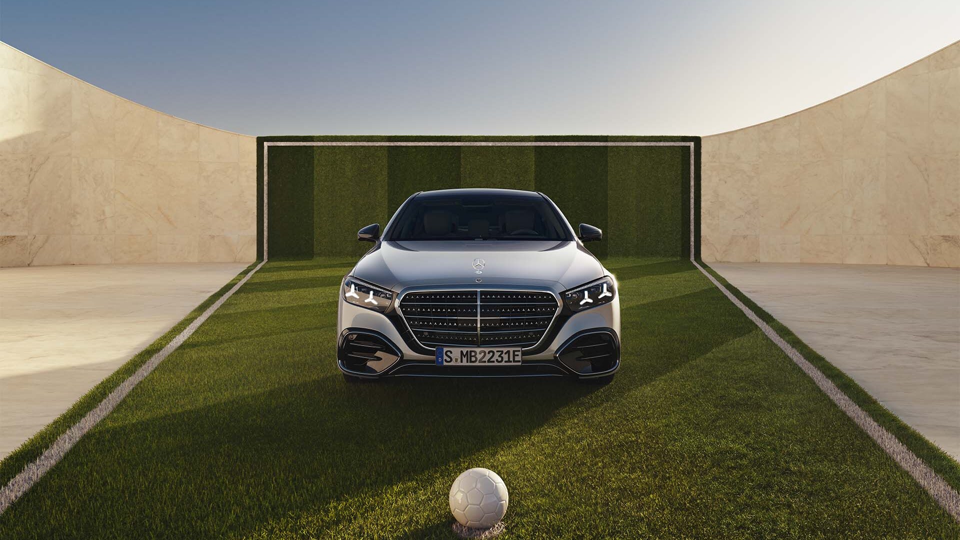 Eine S-Klasse in Frontalansicht auf einem Fußballfeld. Vor dem Mercedes-Benz Modell liegt ein Fußball.