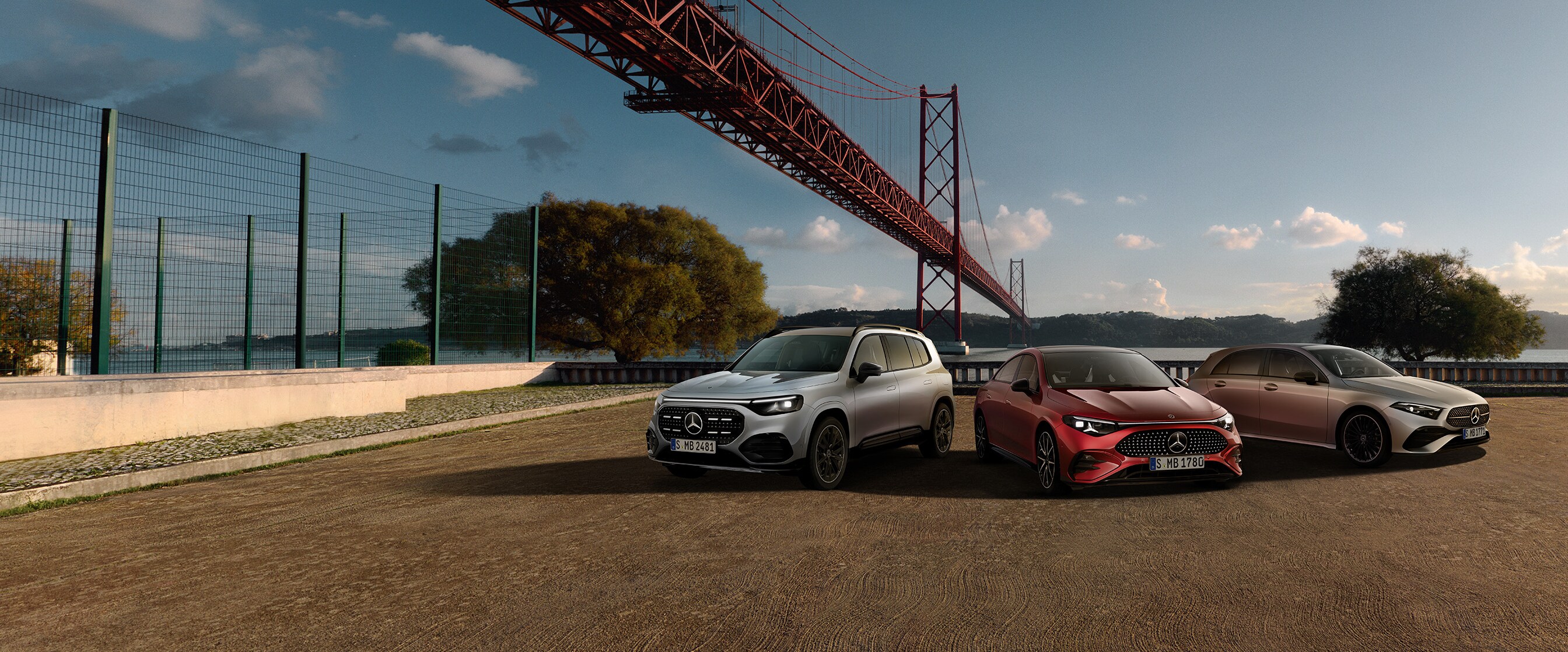 Rangemotive von Mercedes-Benz in Rot und Silber vor einer Brücke am Wasser in Frontalansicht.