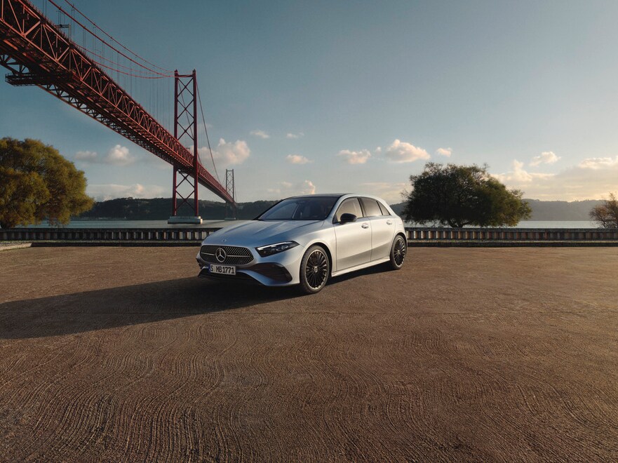 Die Mercedes-Benz A-Klasse in Frontalasicht steht vor einer Brücke am Wasser im Sonnenuntergang.