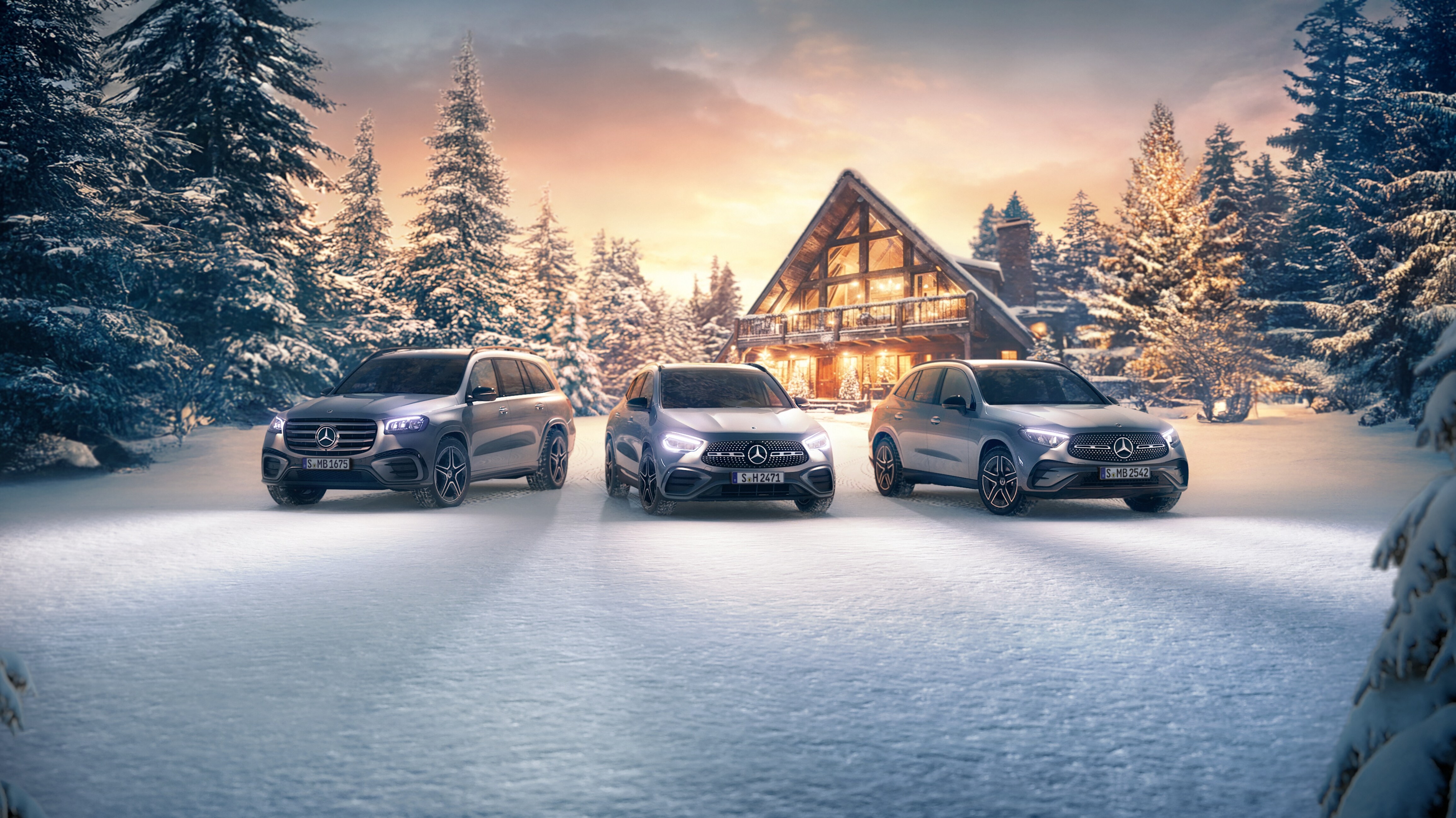 3 Mercedes-Benz Fahrzeuge vor einem beleuchteten Haus in einer Winterlandschaft.