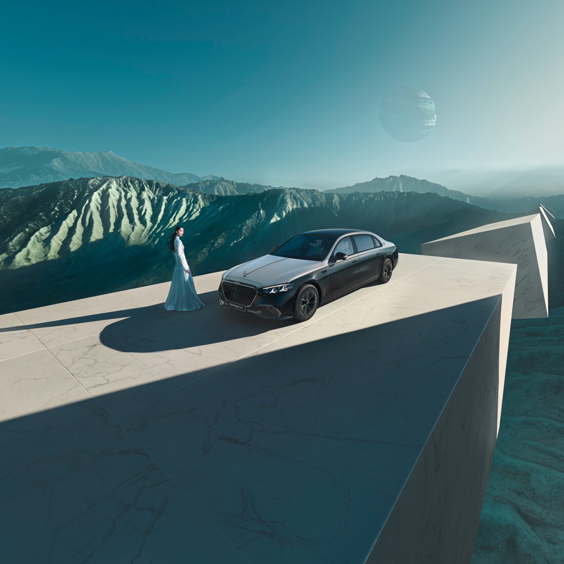 Eine Frau steht neben einer parkenden Mercedes-Maybach S-Klasse. Im Hintergrund eine Bergkulisse.