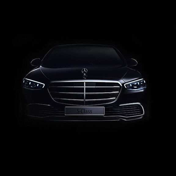 Eine schwarze S-Klasse auf schwarzem Hintergrund. Silberne Kühlerverkleidung aktzentuiert die Silhouette.