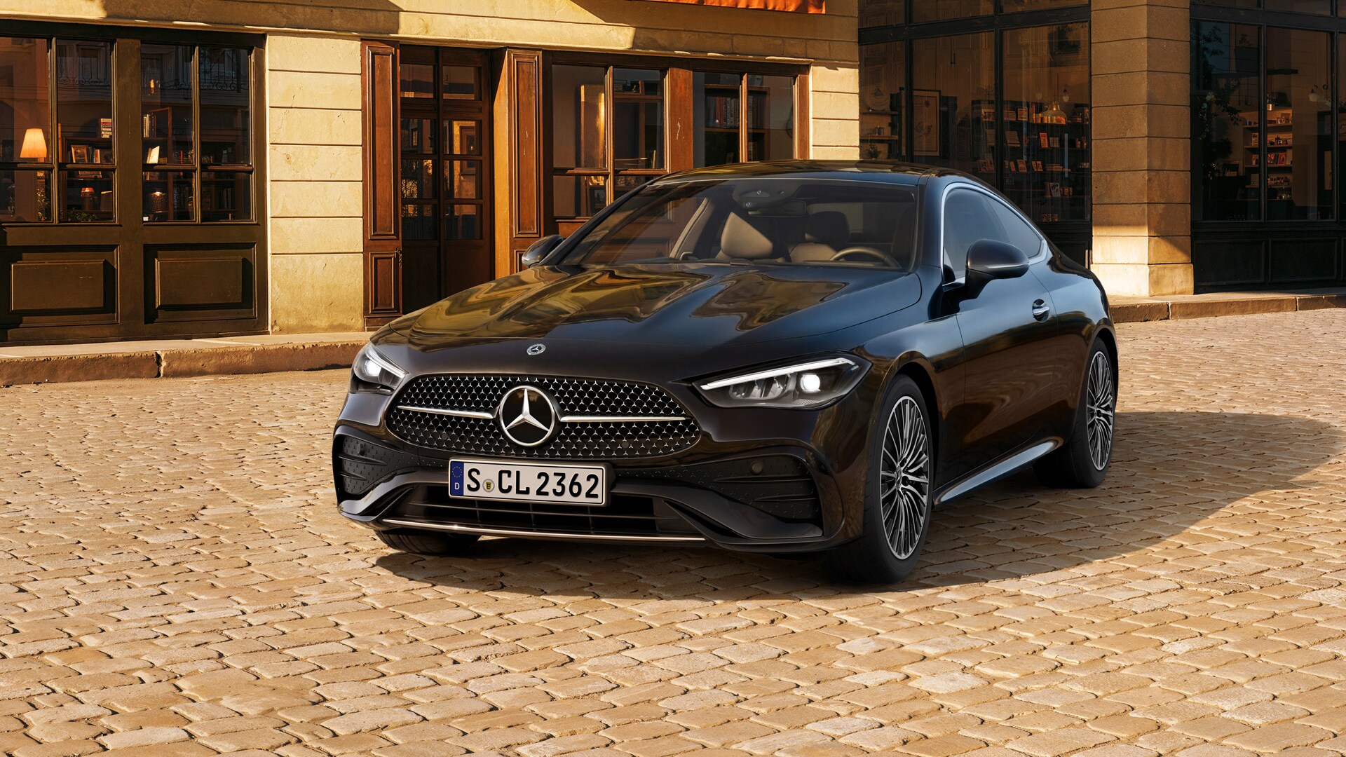 Ein schwarzer Mercedes-Benz CLE Coupé seitlicher Frontansicht, parkend vor einem Bistro.