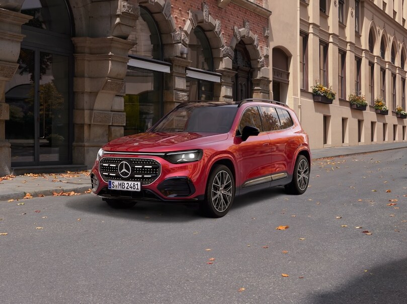 Ein roter Mercedes-Benz GLB steht in der Stadt auf einer Straßenecke bei herbstlichem Wetter.