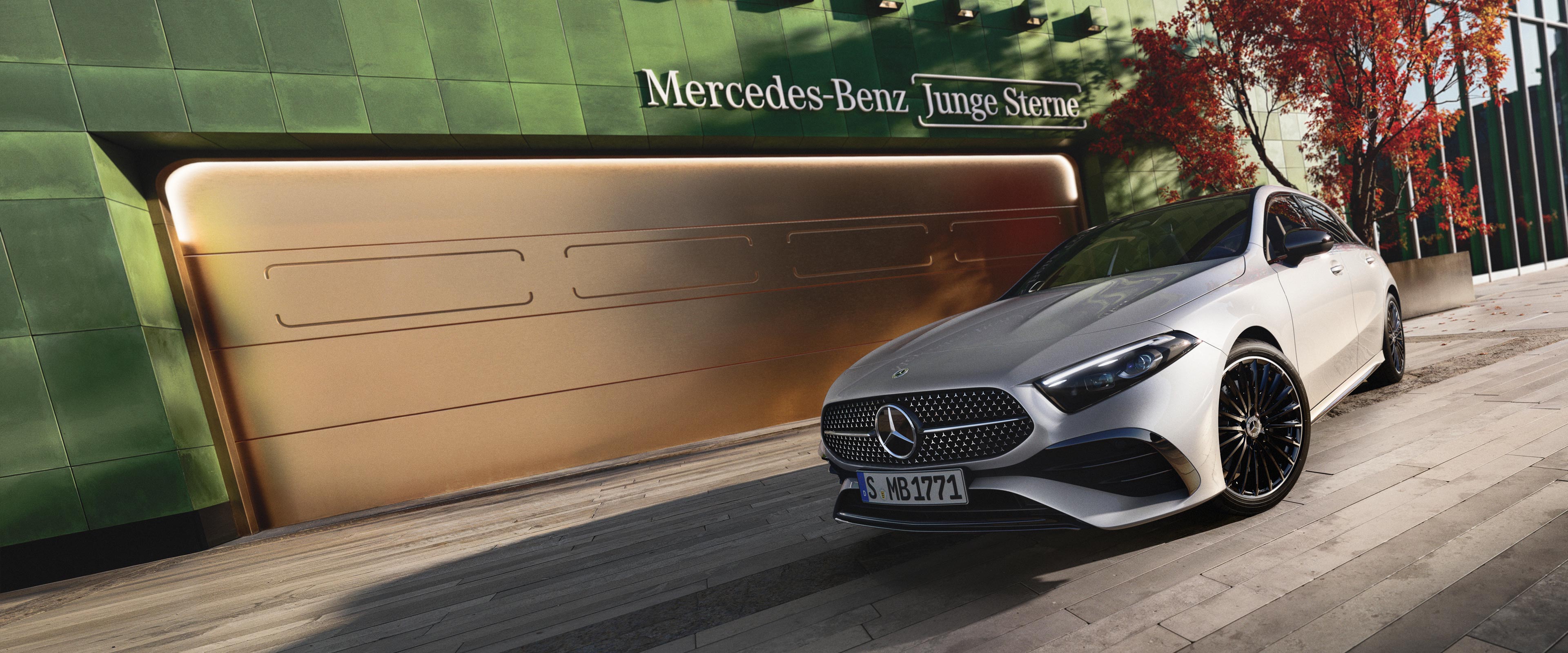 Junge Sterne | Mercedes-Benz Ein Mercedes-Benz Modlel in herbstlicher Kulisse stehend vor einem Tor.