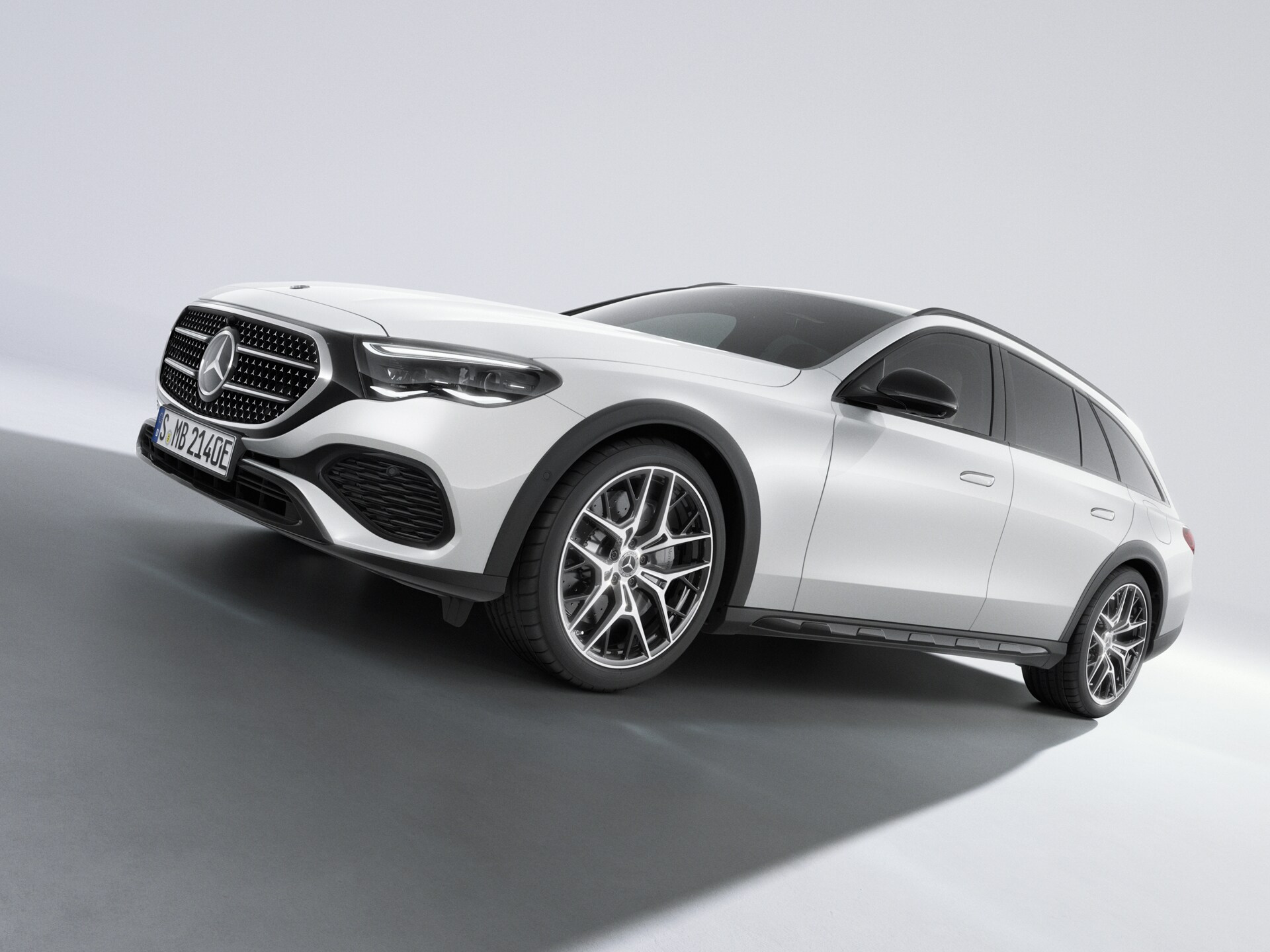 Ein weißes Mercedes-Benz E-Klasse T-Modell in der seitlichen Frontansicht auf hellem Untergrund.
