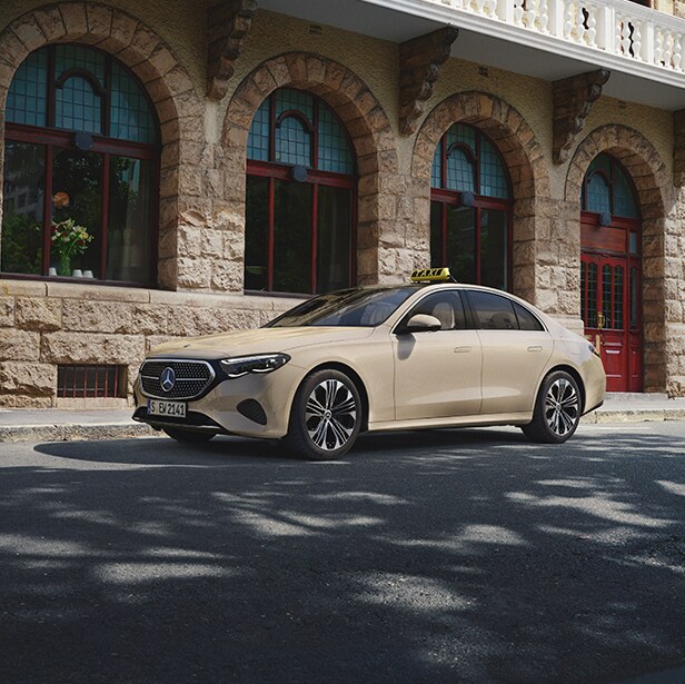Eine Mercedes-Benz E-Klasse als Taxi steht am Starßenrand vor einer Häuserfront.