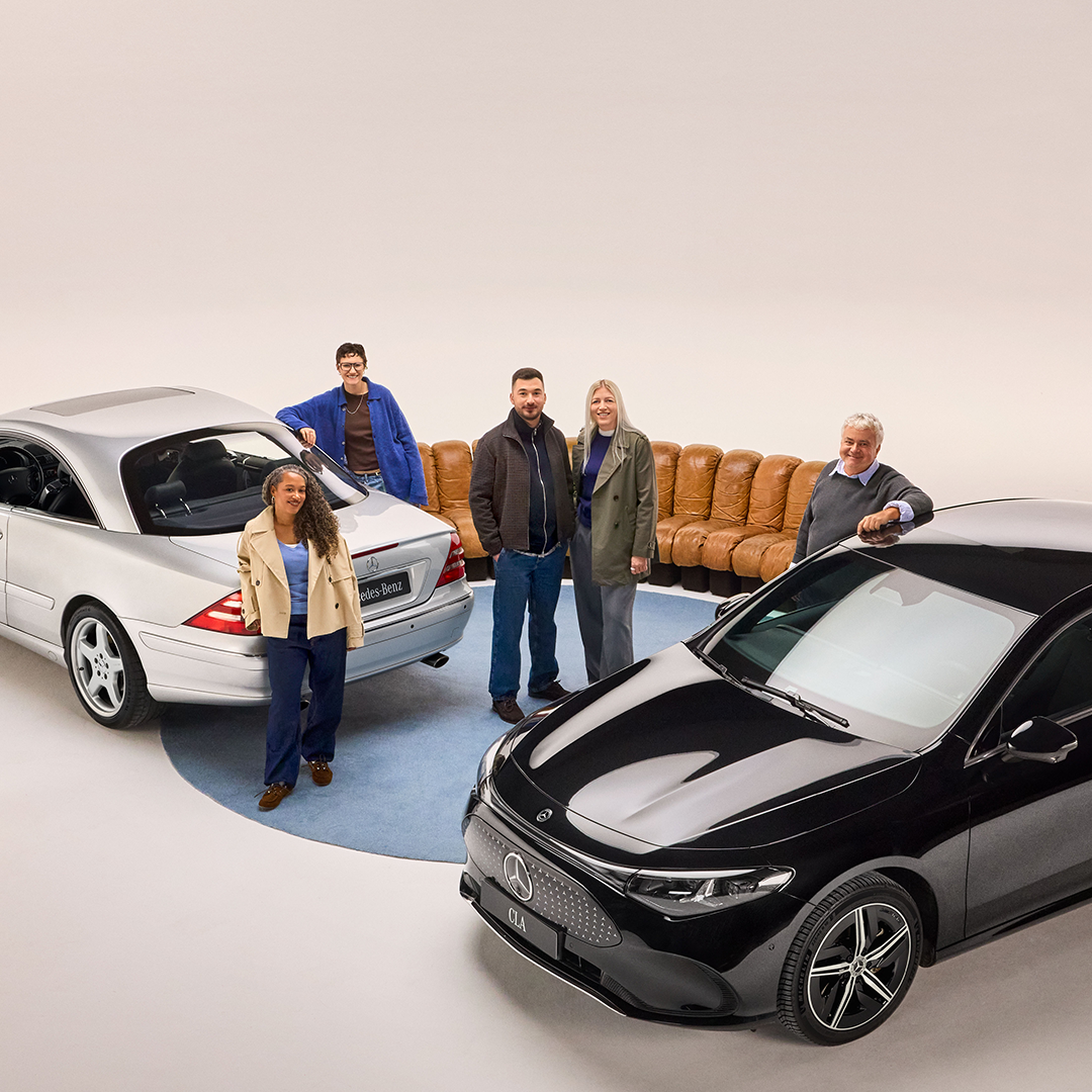 Aktuelles zum Kundencenter | Mercedes-Benz. Fünf Personen stehen zwischen einem silbernen und einem schwarzen Mercedes-Benz in einem hell beleuchteten Studio, mit einem beigefarbenen Sofa im Hintergrund.