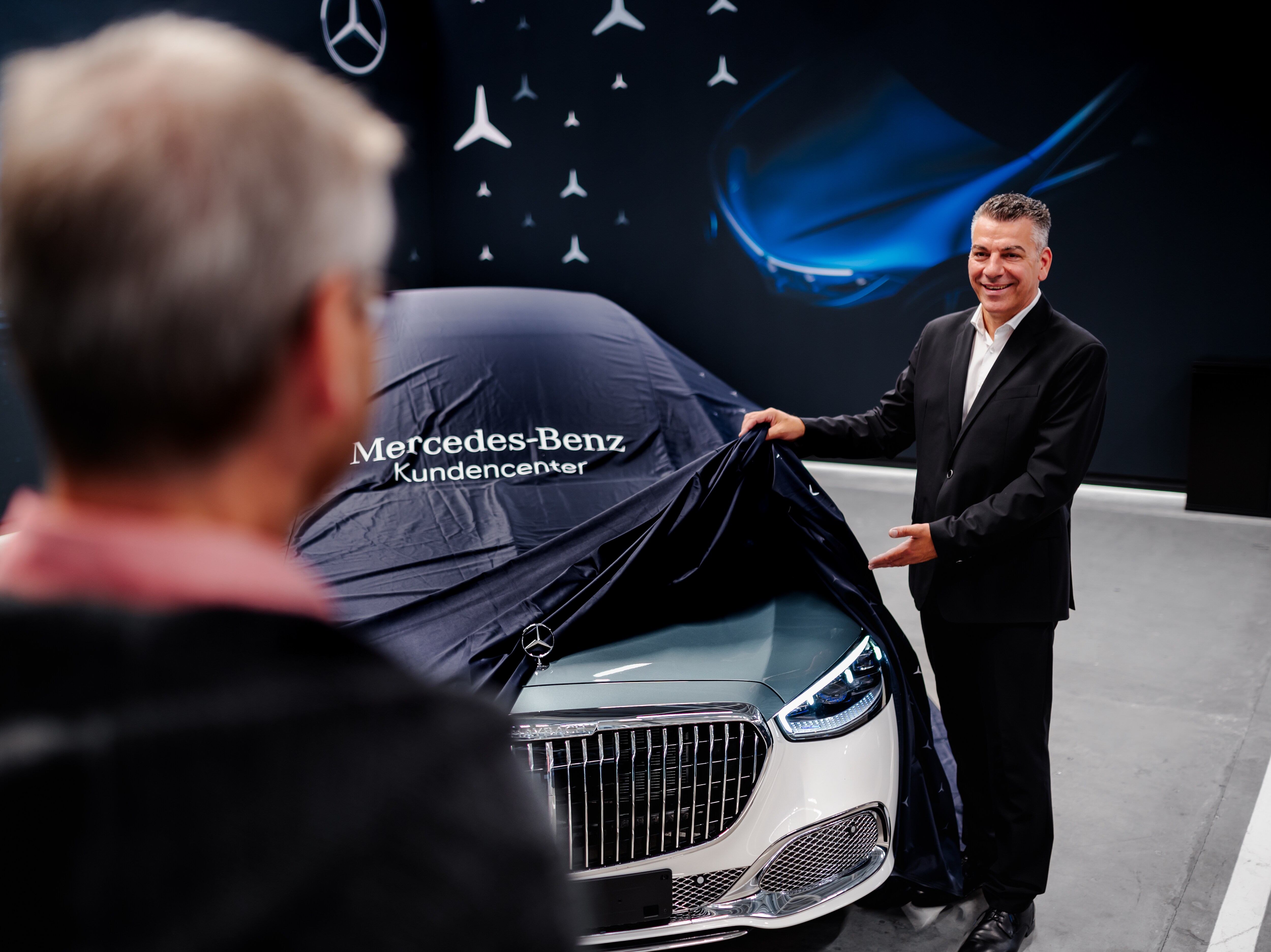 Zwei Männer stehen an einem Mercedes-Benz Modell, das abgedeckt wird.