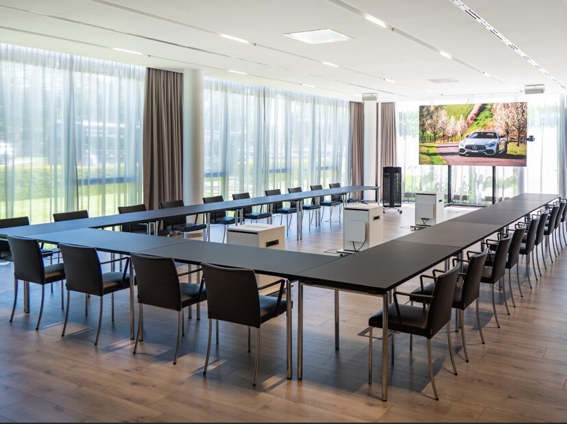 Ein lichtdurchfluteter Konferenzraum mit u-förmig angeordnetem Tisch und Stühlen drumherum.