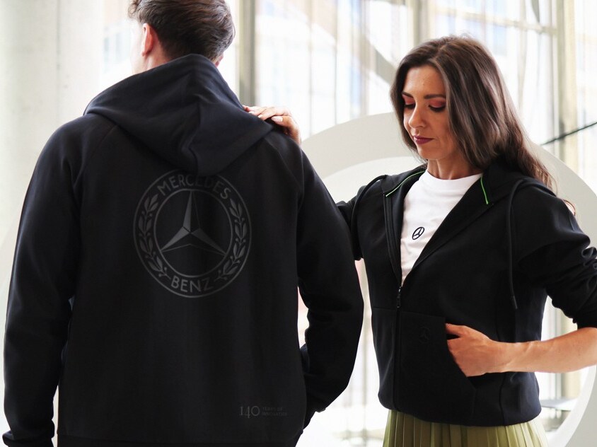 Ein Pärchen in Mercedes Benz Outfit steht in einer Licht durchfluteten Eingangshalle.