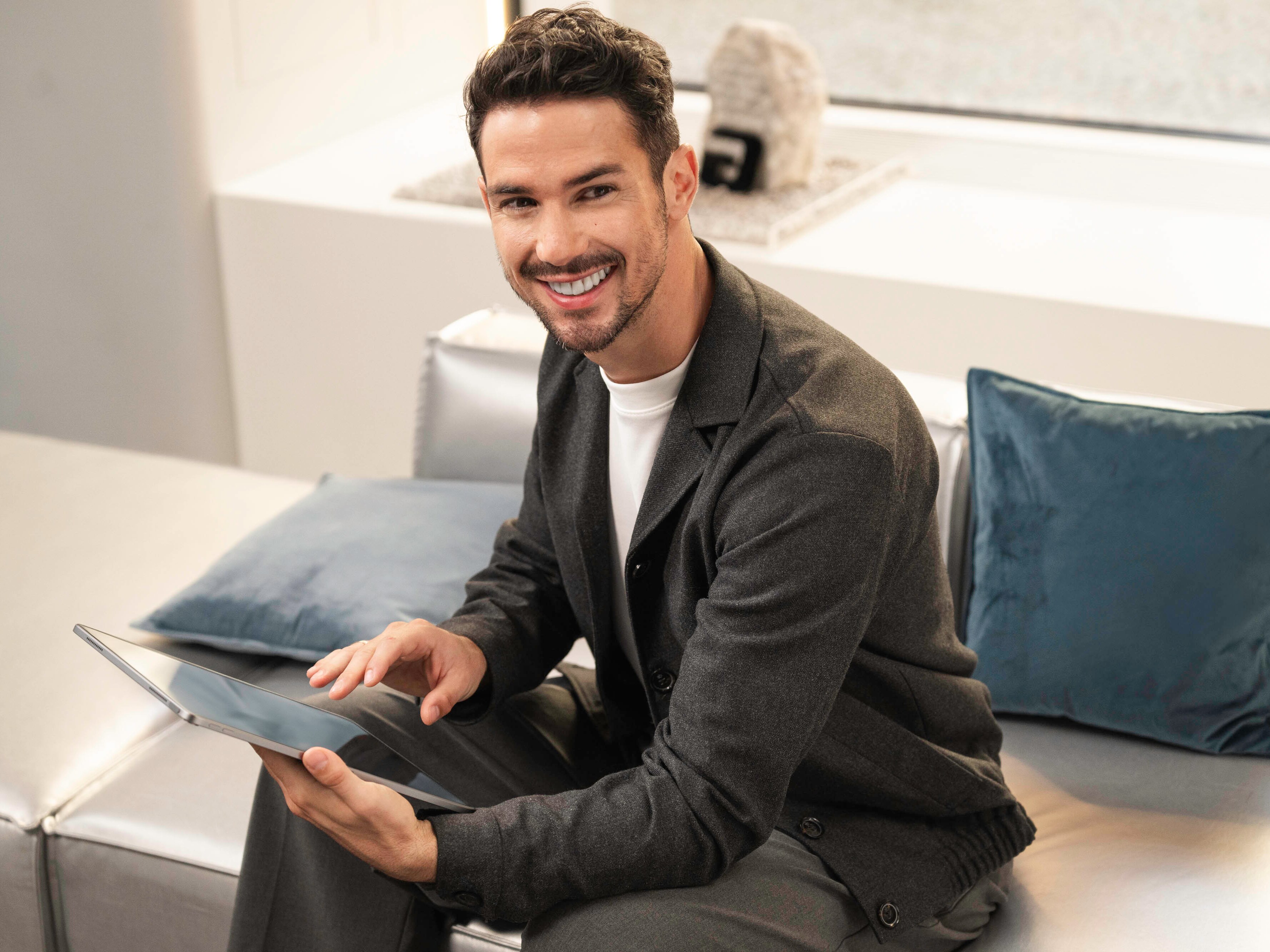 Eine Person sitzt auf der Couch und benutzt ein mobiles Gerät.