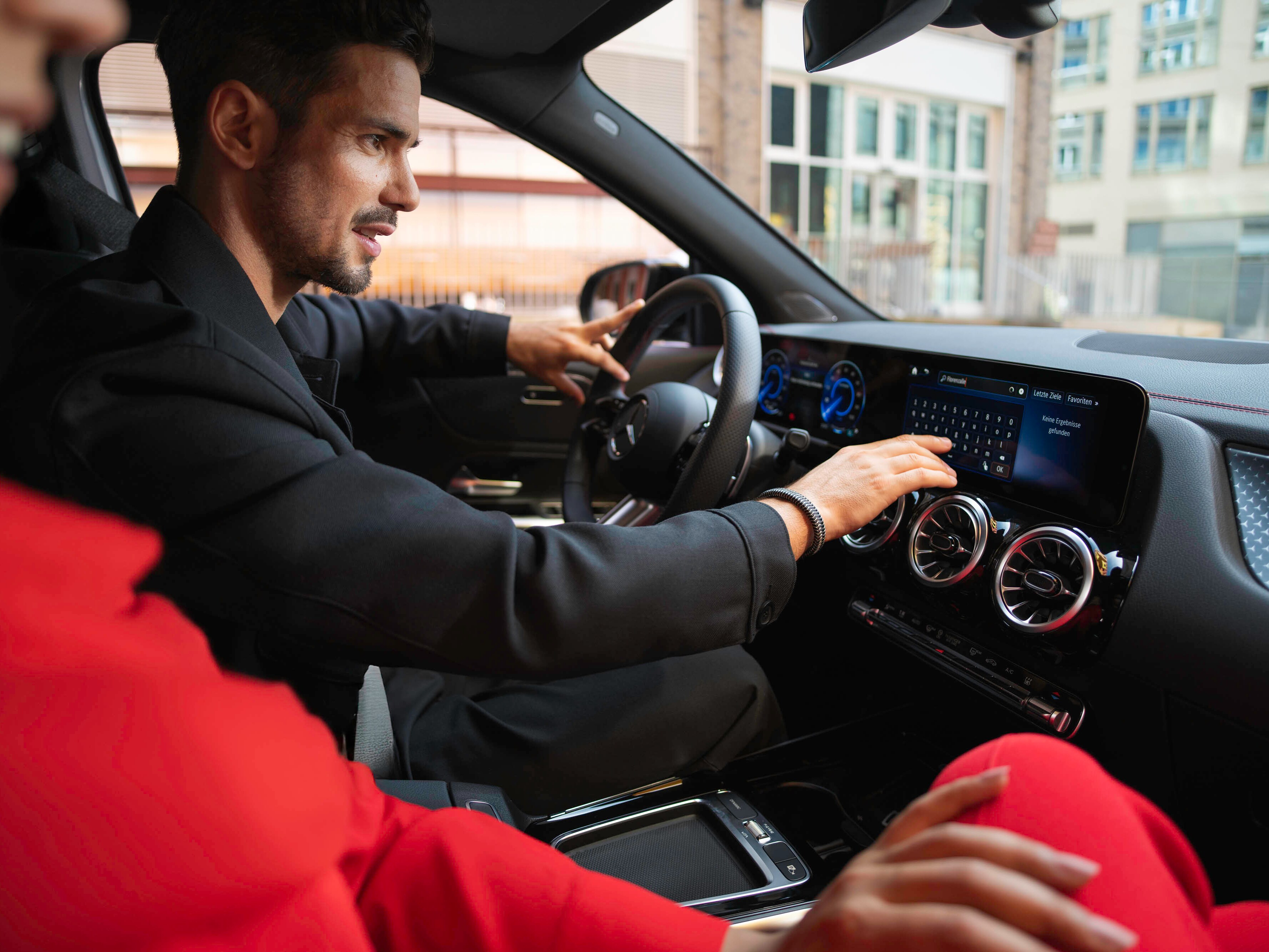 Eine Person steht auf der Straße mit einem Mercedes-Benz im Hintergrund.