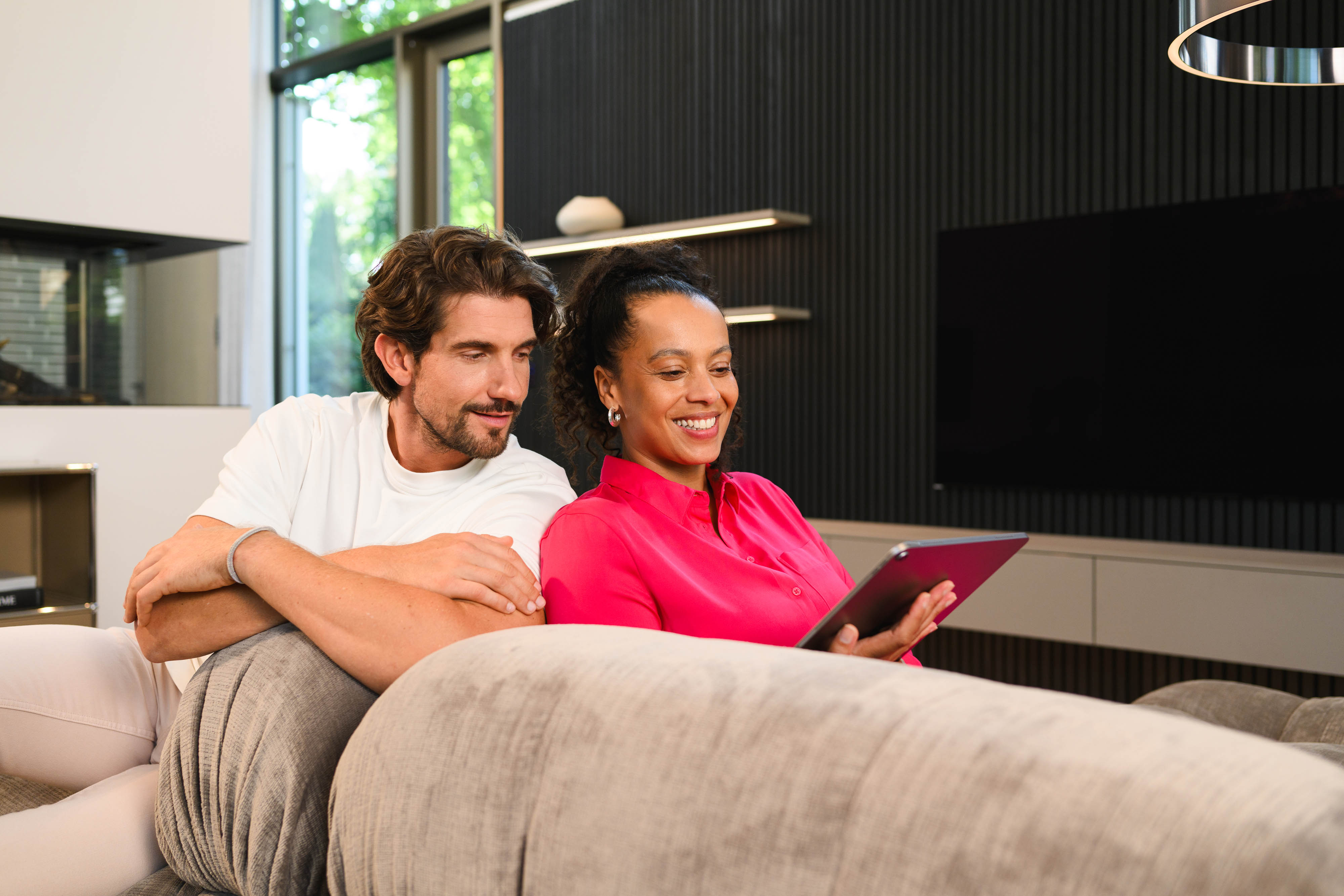 Mercedes-Benz Financial Services im Überblick | Aktuelle Angebote Zwei Menschen auf der Couch schauen auf ein Tablet.