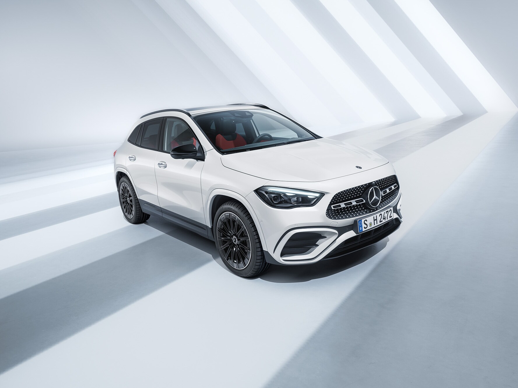 Ein weißer Mercedes-Benz GLA 180, parkend vor einer weißen von Sonnenstrahlen durchfluteten Raum.