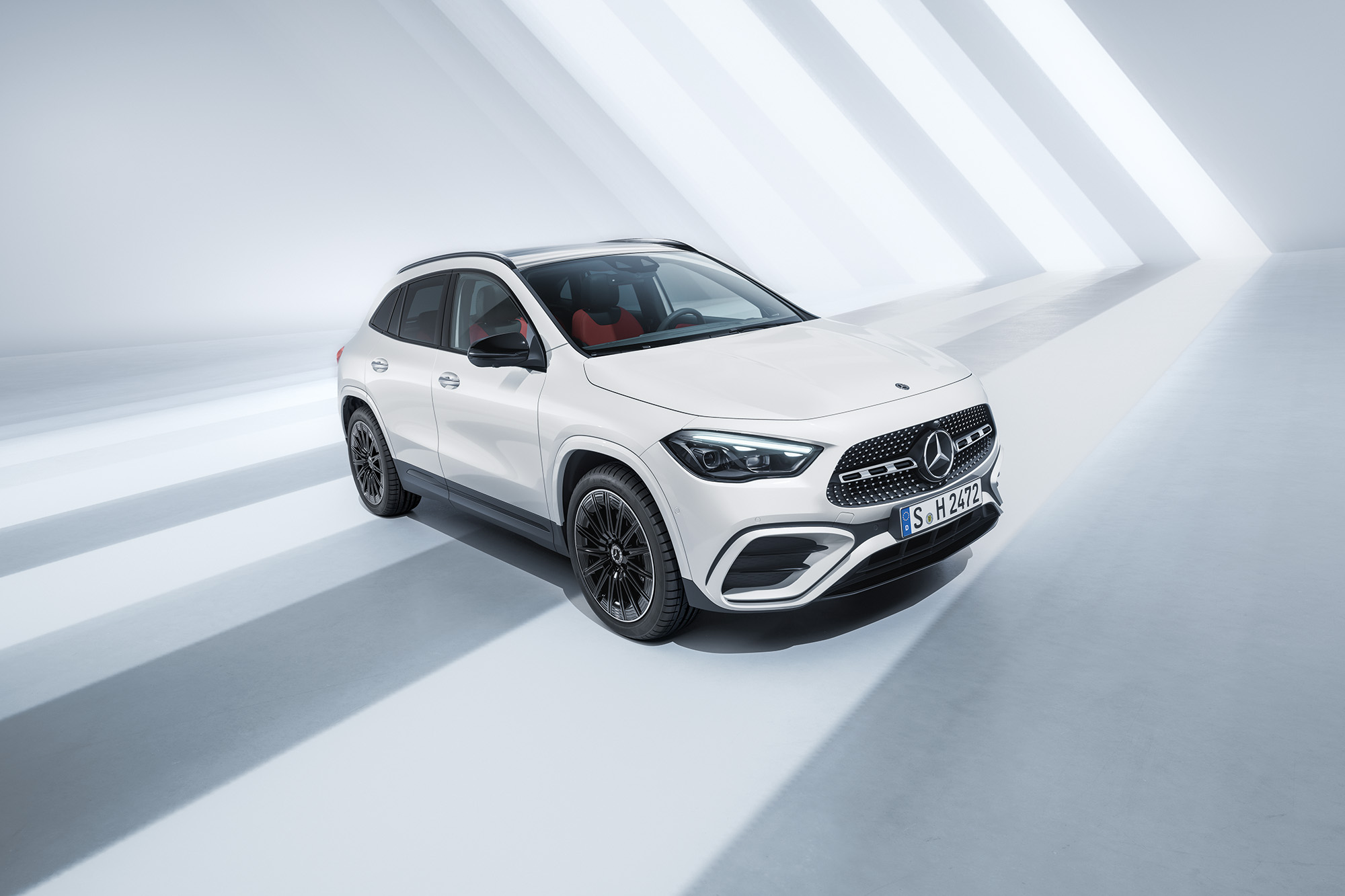 Fahrzeug-Angebote | Mercedes-Benz. Ein weißer Mercedes-Benz GLA 180, parkend vor einer weißen von Sonnenstrahlen durchfluteten Raum.