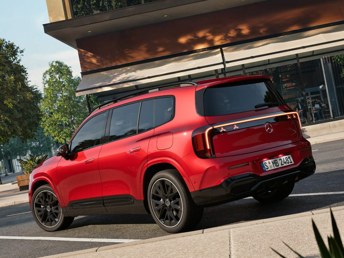 Ein roter GLB SUV steht auf einem sonnigen Parkplatz vor einem braunen Gebäude.