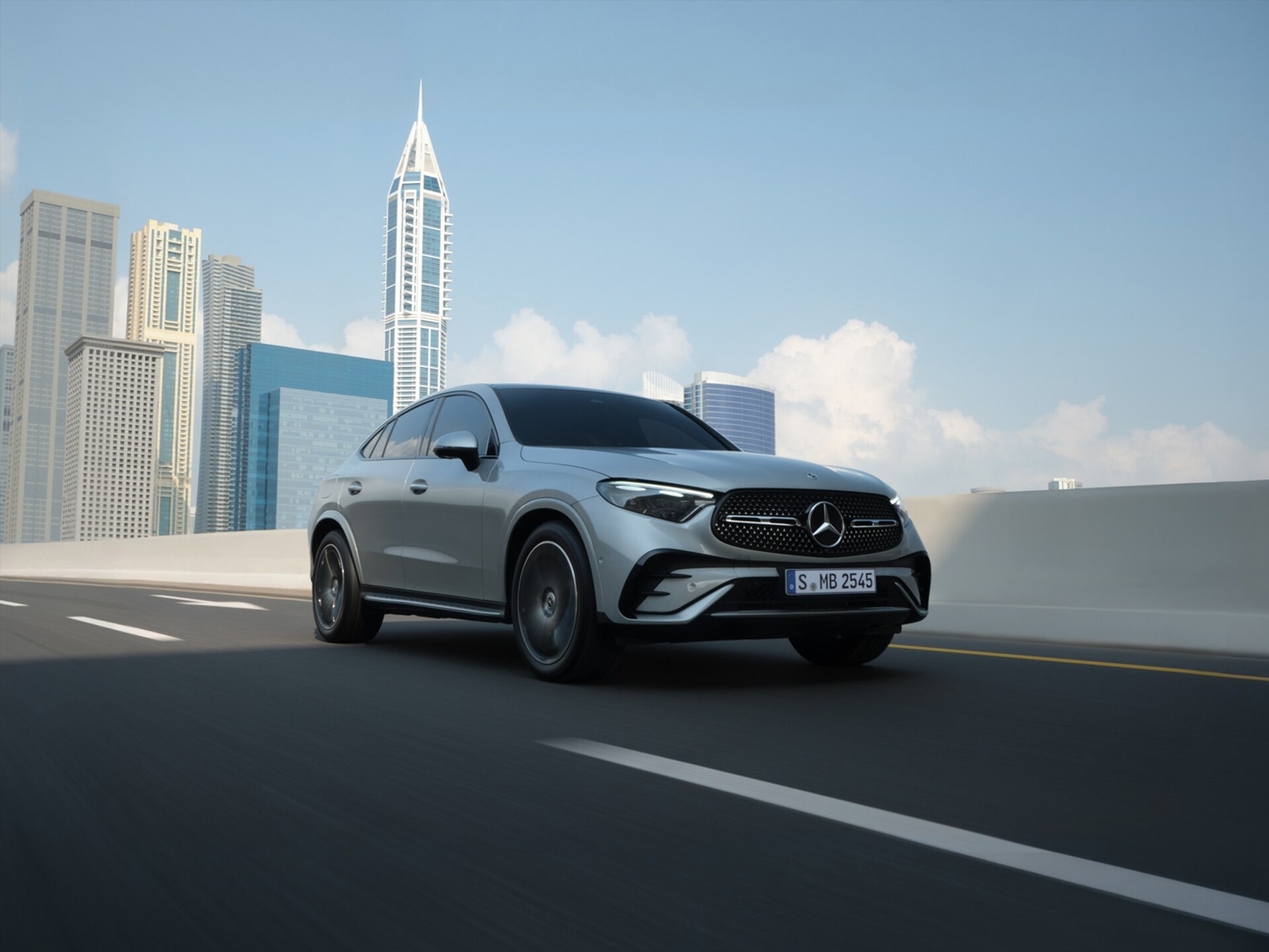 Ein silbernes Mercedes-Benz GLC Coupé fährt Stadt mit Hochhäusern im Hintergrund.
