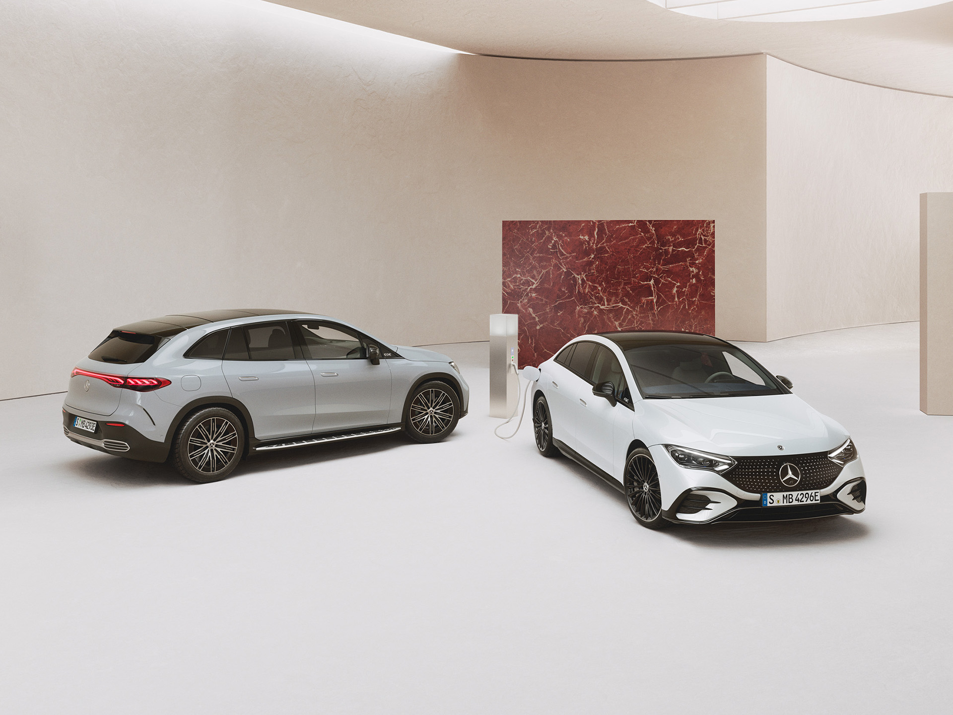 Elektroauto Förderung | Mercedes-Benz Mercedes-Benz EQE Limousine und SUV parkend in einem Showroom vor hellem Hintergrund.