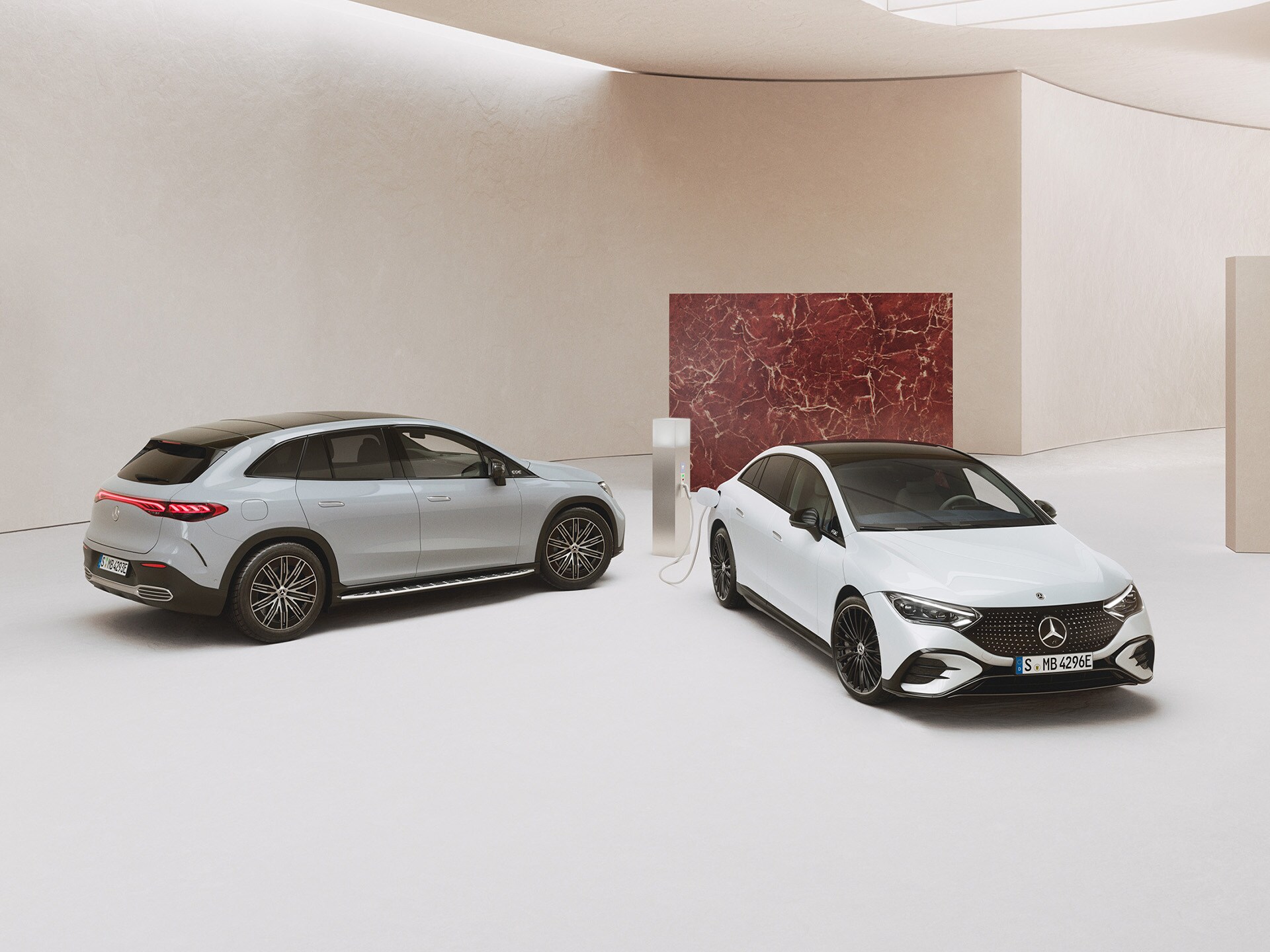 Mercedes-Benz EQE Limousine und SUV parkend in einem Showroom vor hellem Hintergrund.