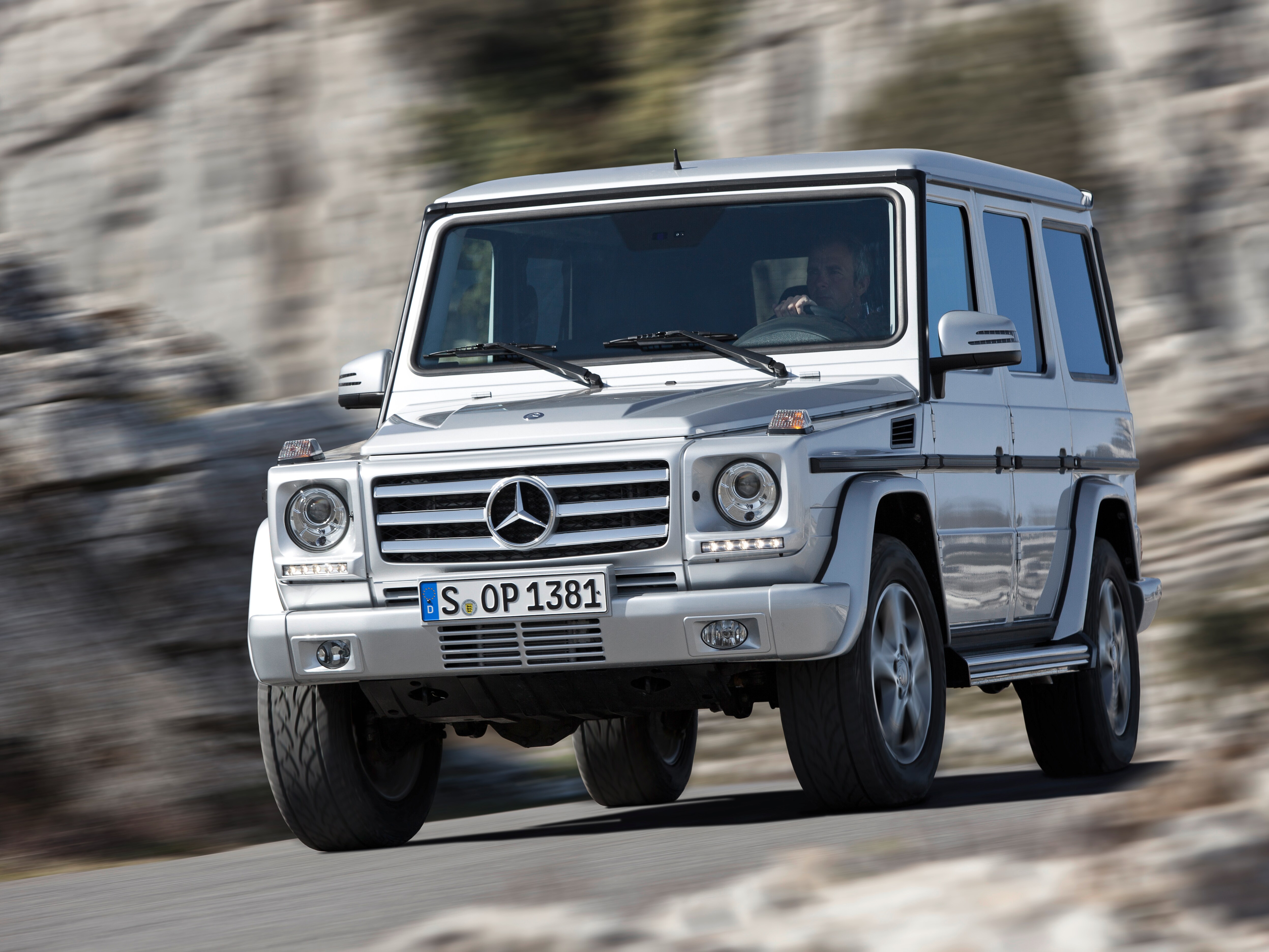 Eine silberne G-Klasse von Mercedes-Benz in Bewegung vor einer steinernen Felswand.